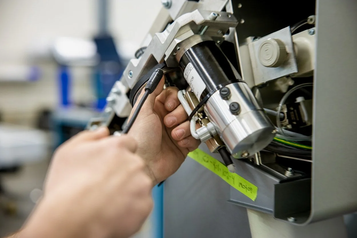 Close-up of a Hexagon associate working with high-tech manufacturing equipment in North Kingstown, Rhode Island.