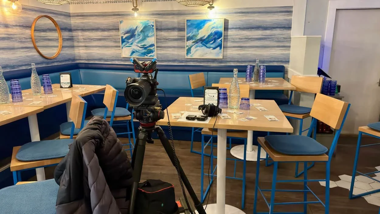 Single-camera video production setup in a restaurant event space before a live fireside chat