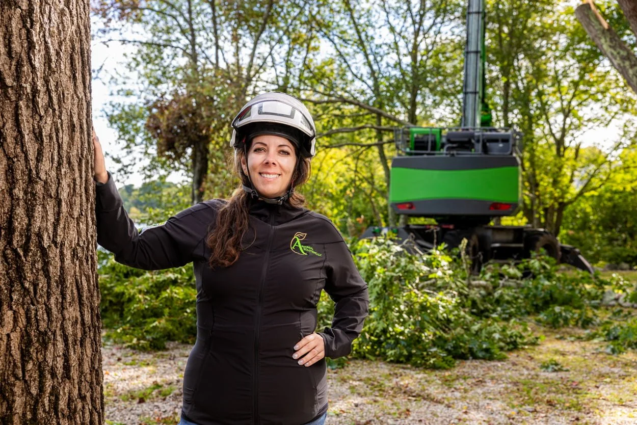 employee in branded workwear and helmet standing at outdoor job site with equipment