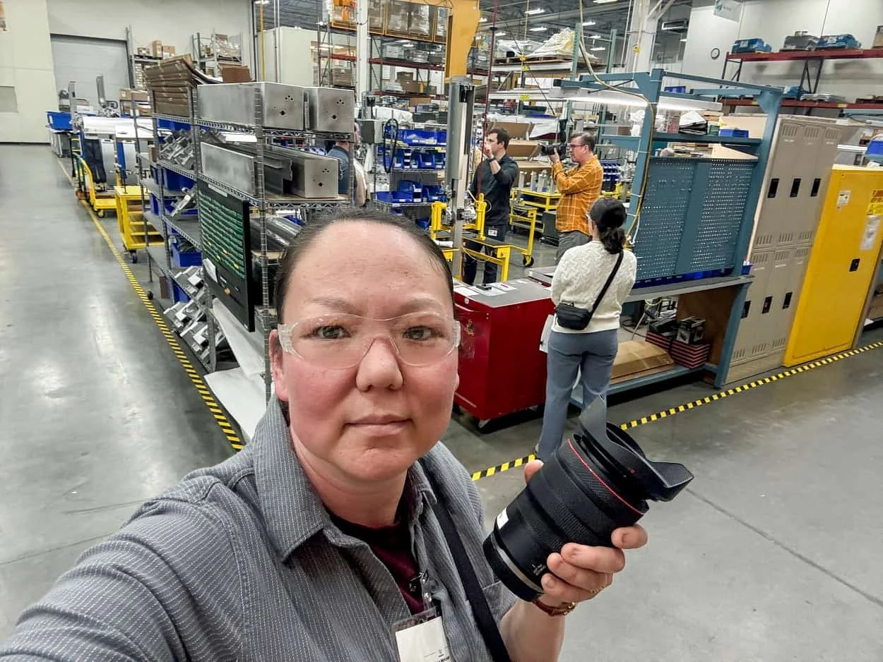 Photography assistant carrying equipment through a manufacturing facility while supporting a commercial photography project.