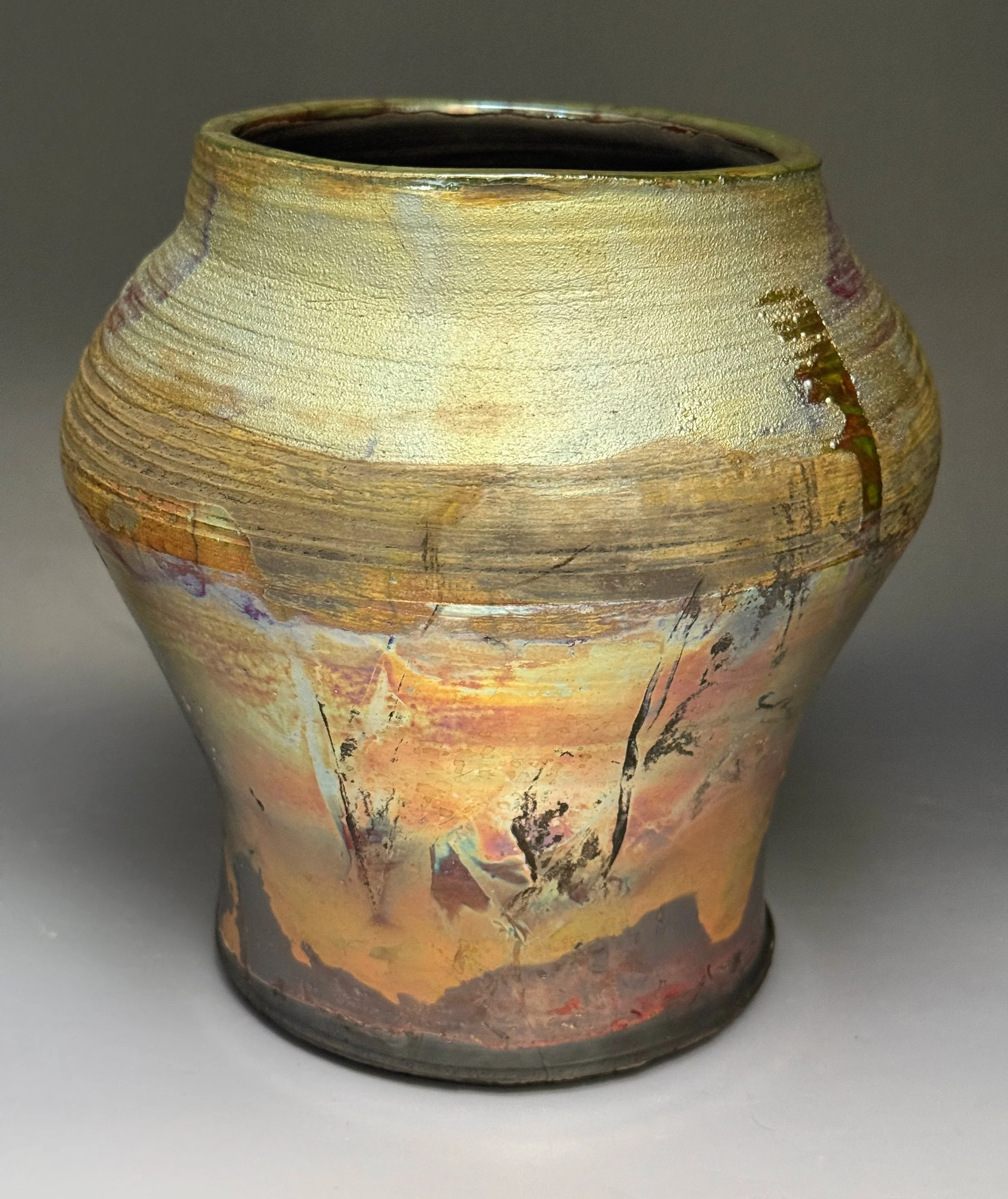 An artistic ceramic vase with a glossy, multicolored glaze featuring earthy tones and abstract patterns.