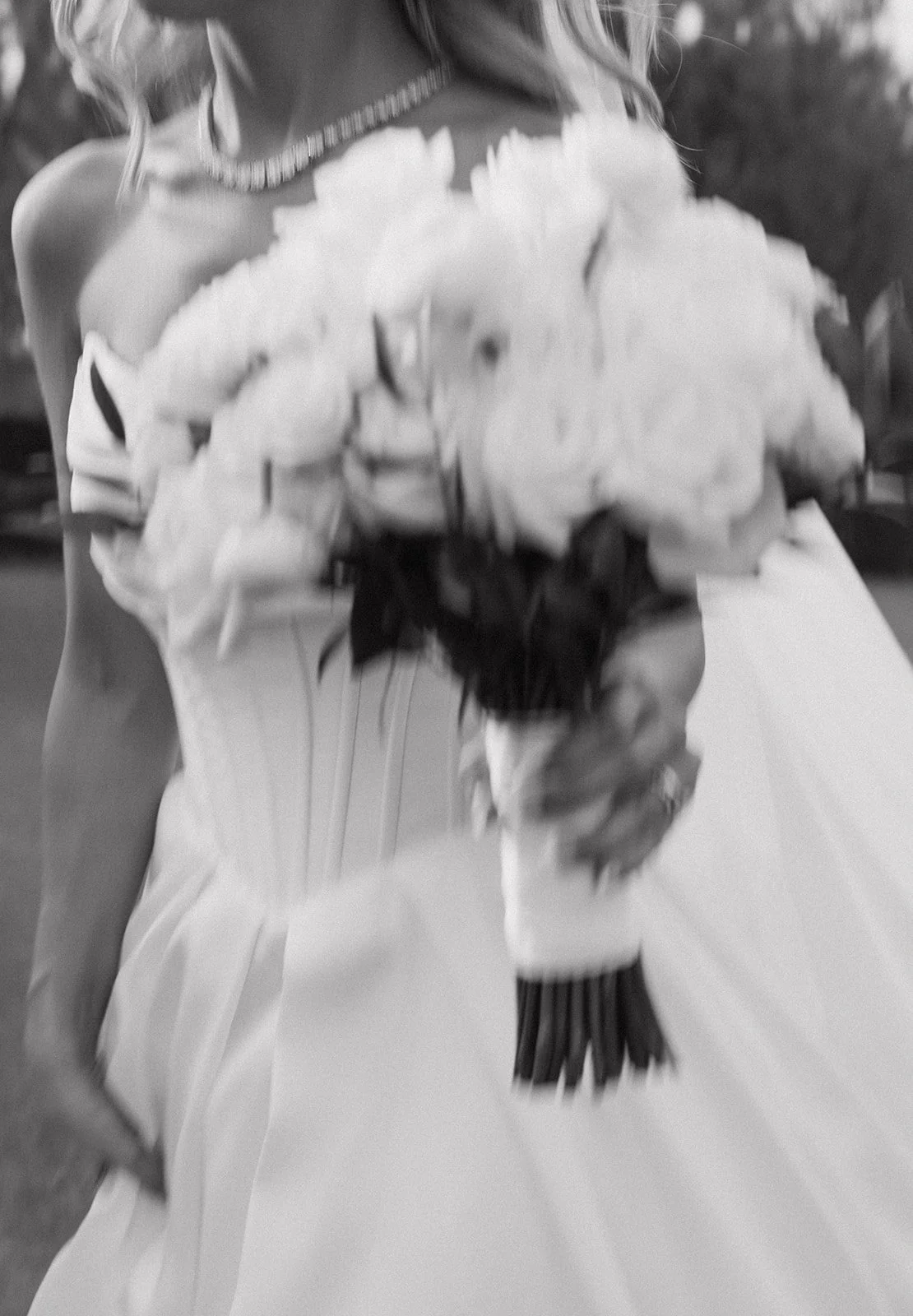 A bride holding a large bouquet of flowers in her wedding dress.