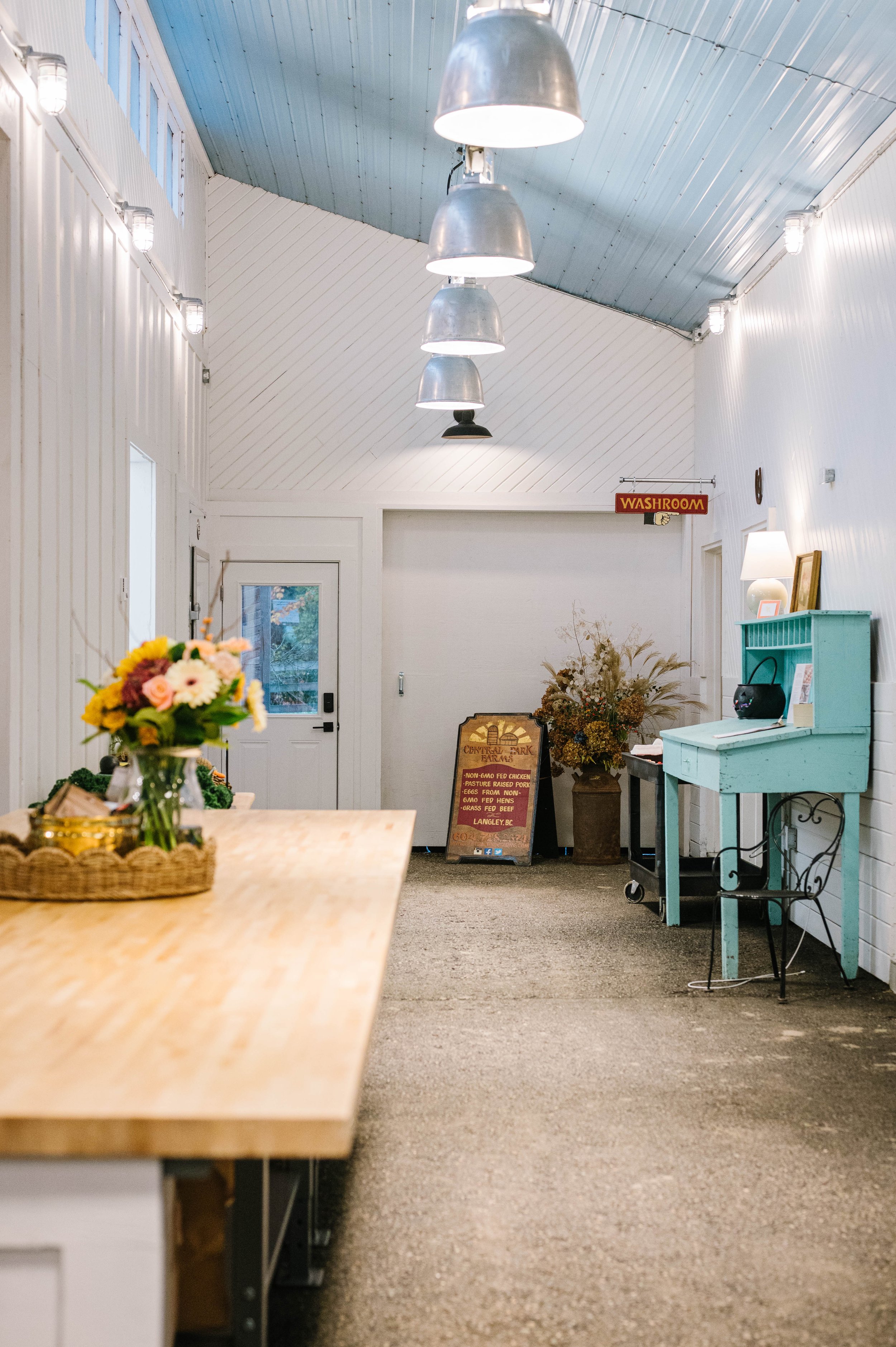 Inside a farm store with white walls, a blue roof, and big hanging lights