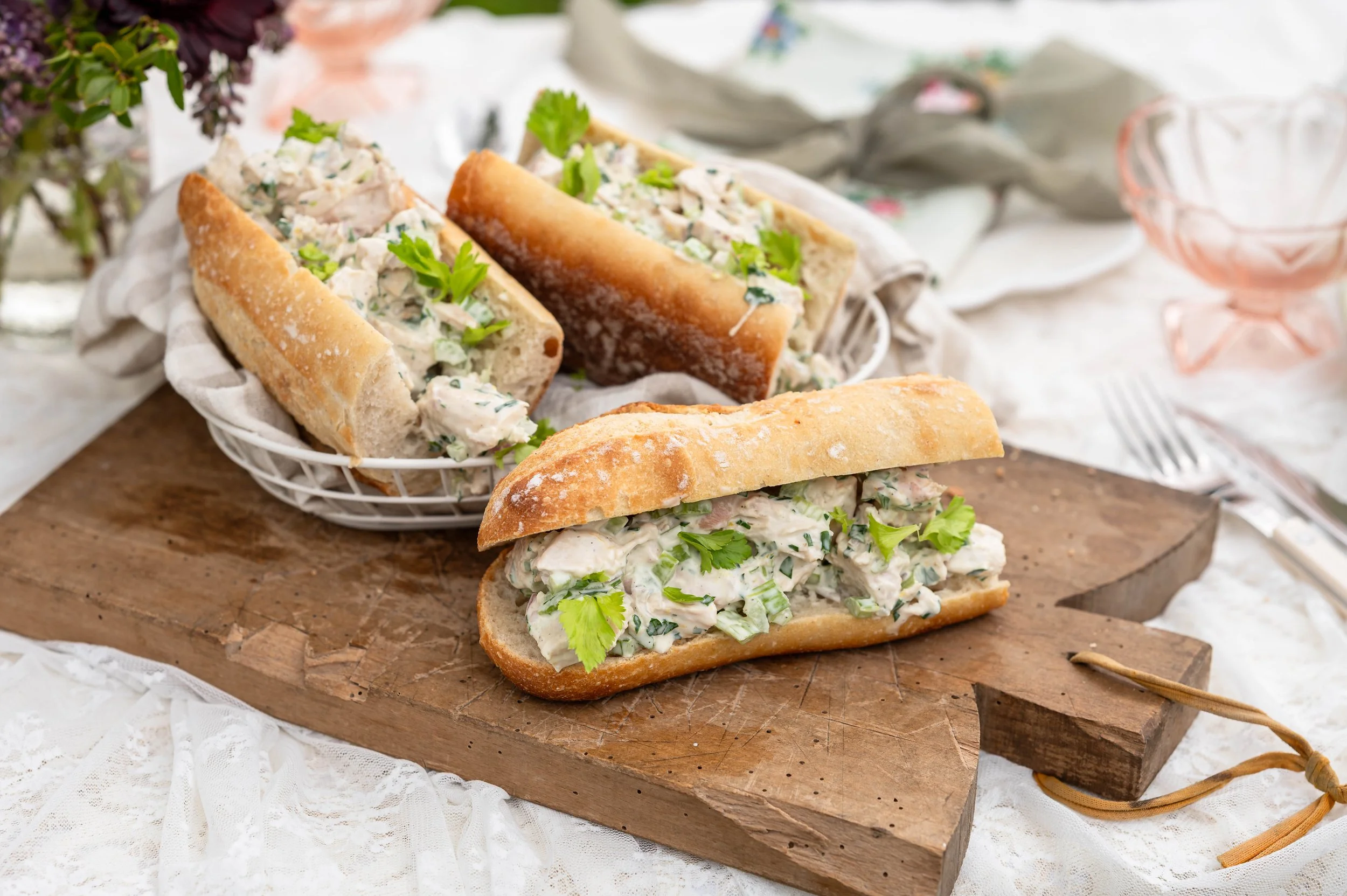 A close up of three chicken salad sandwiches on a wood cutting board.