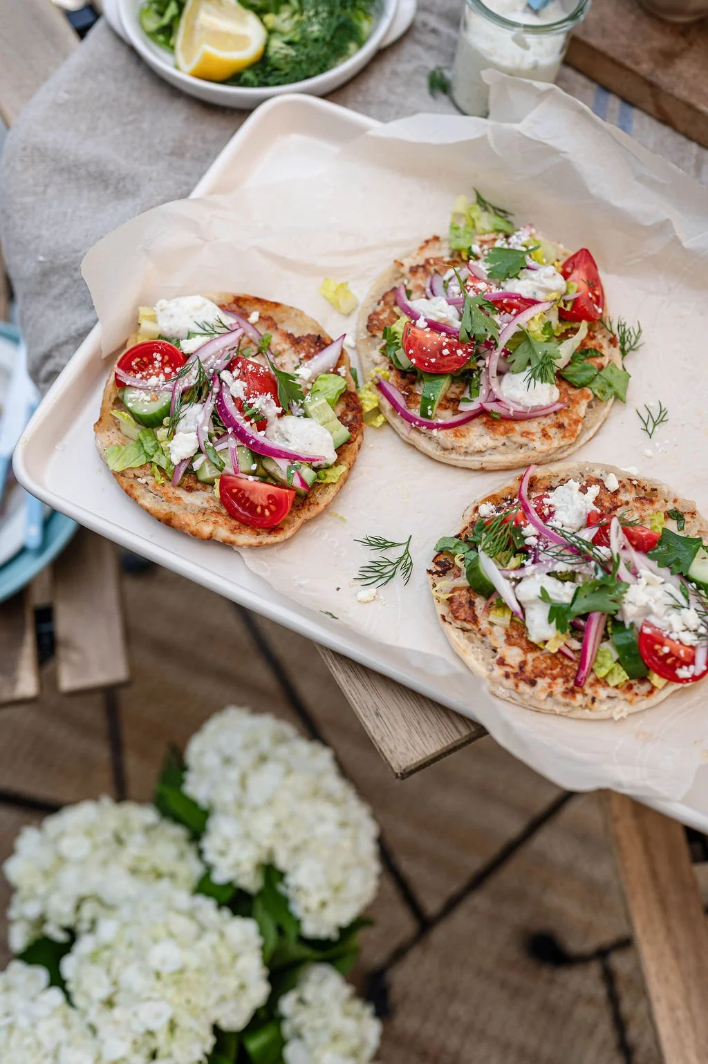 A plate of brightly coloured greek chicken pitas with tomatoes and feta