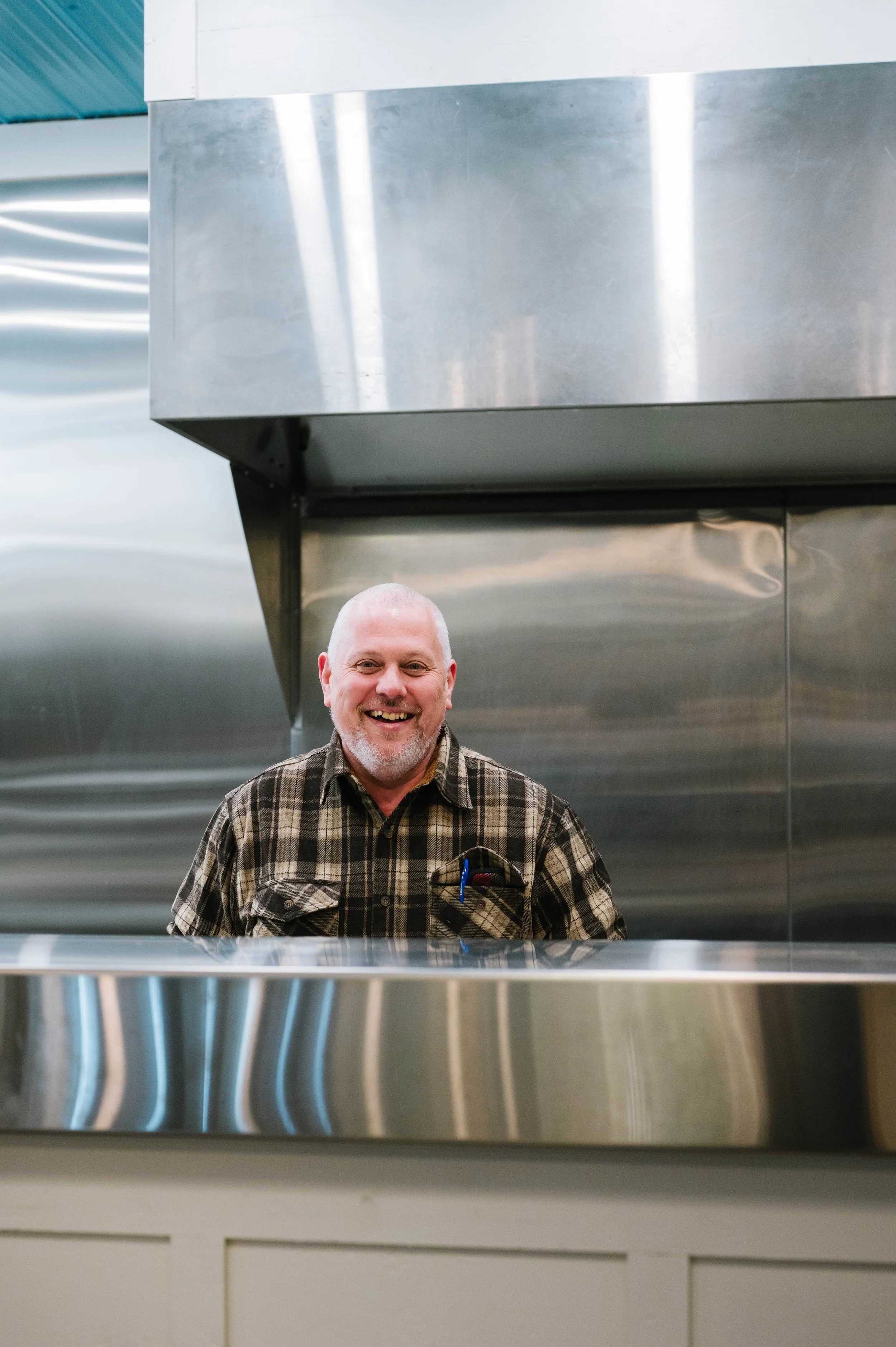 A chef standing in a commercial kitchen with a smile on his face