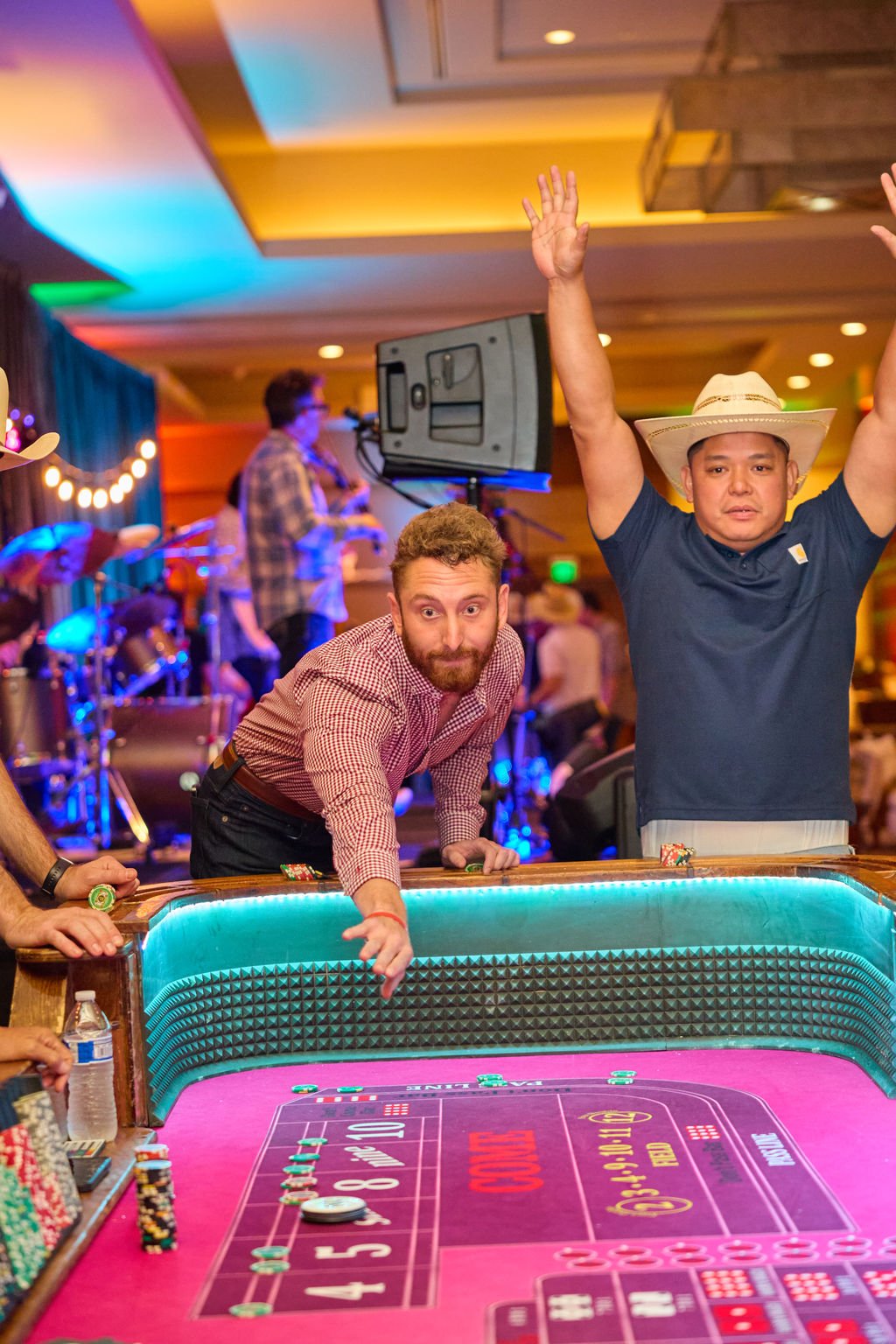 People playing craps at a casino table with a band performing in the background.