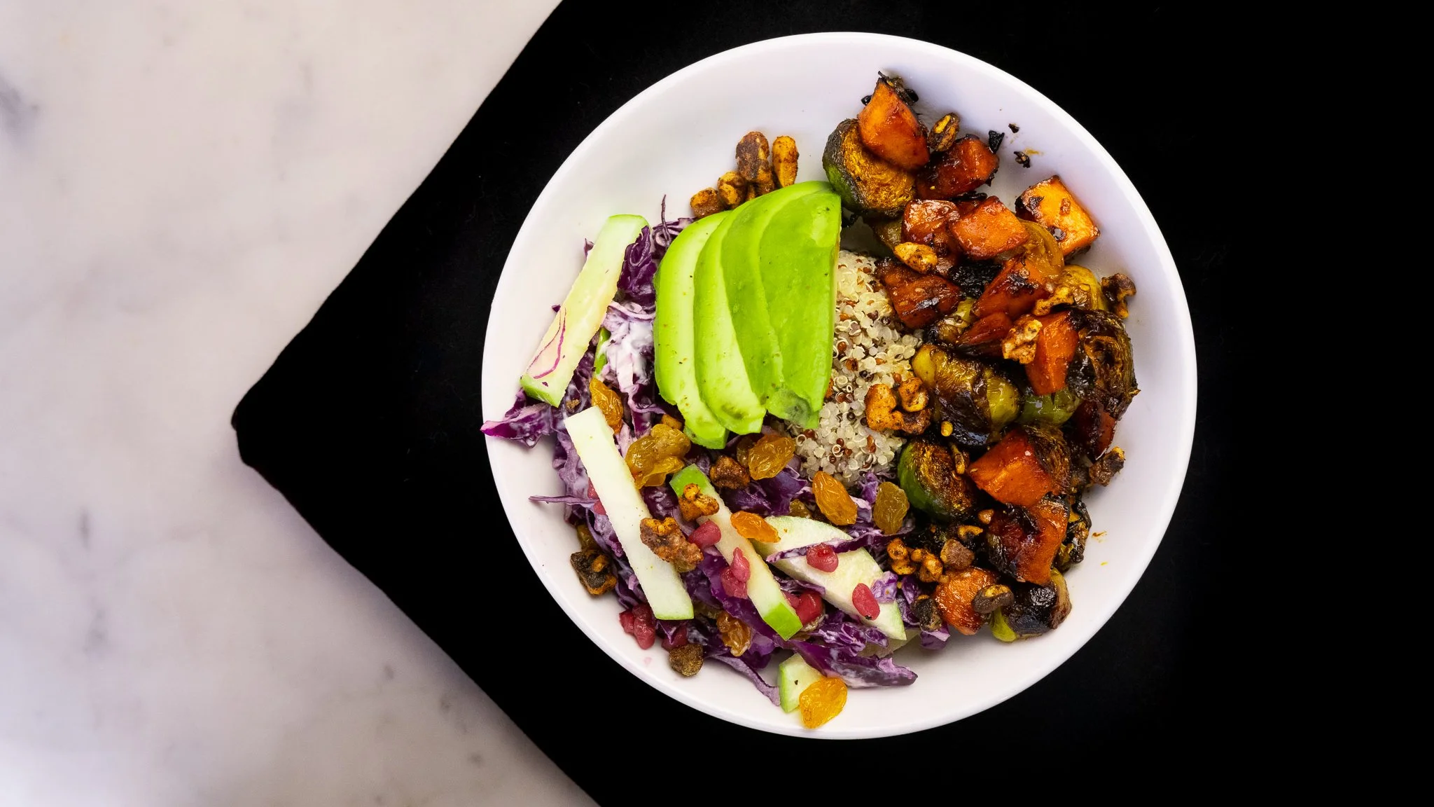 A top down view of the quinoa harvest bowl with sweet potato, apple, and slices of avocado.