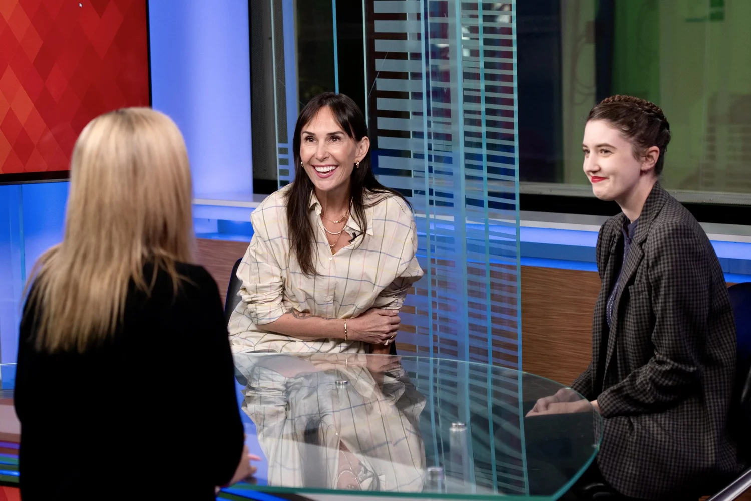 Media training session in a Los Angeles TV studio with Olivia Smith coaching two clients at an interview table