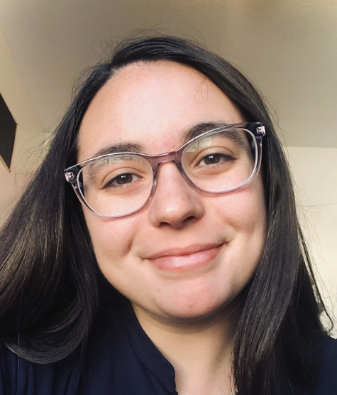 Close-up of a woman with glasses smiling indoors.