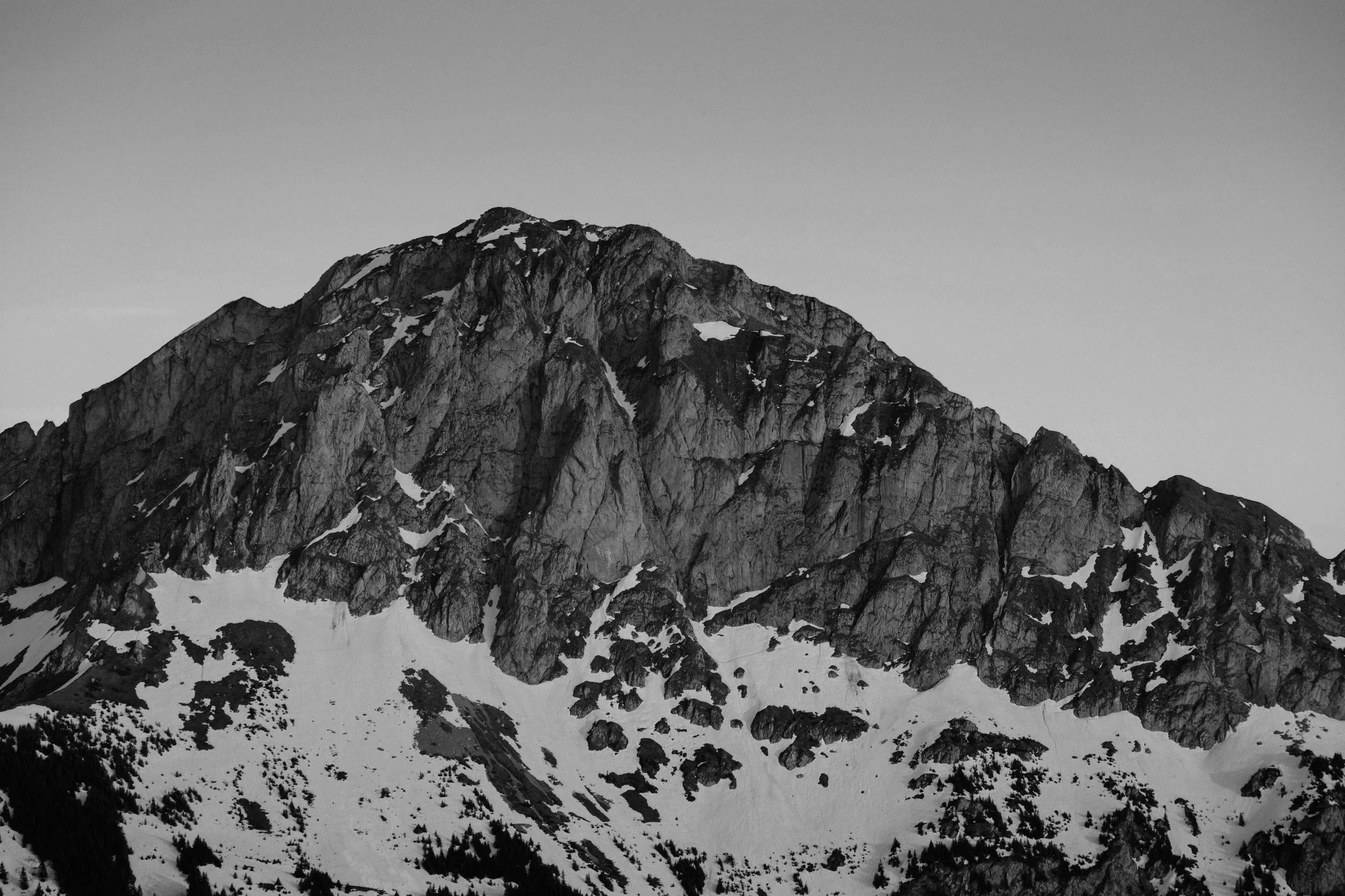 Snow-covered mountain peaks with rocky slopes in black and white