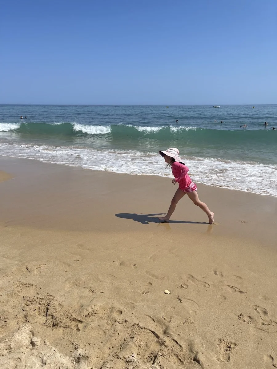 Child playing on the beach in front of waves in Algarve - sand and sea