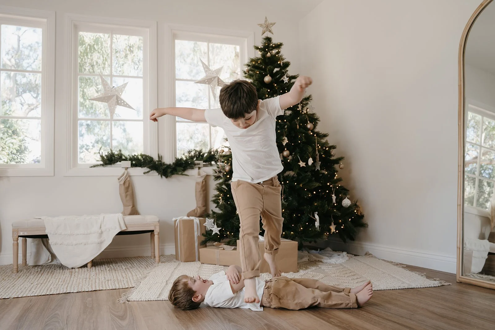 Two young children playing near the christmas tree during a fun christmas family in-home session