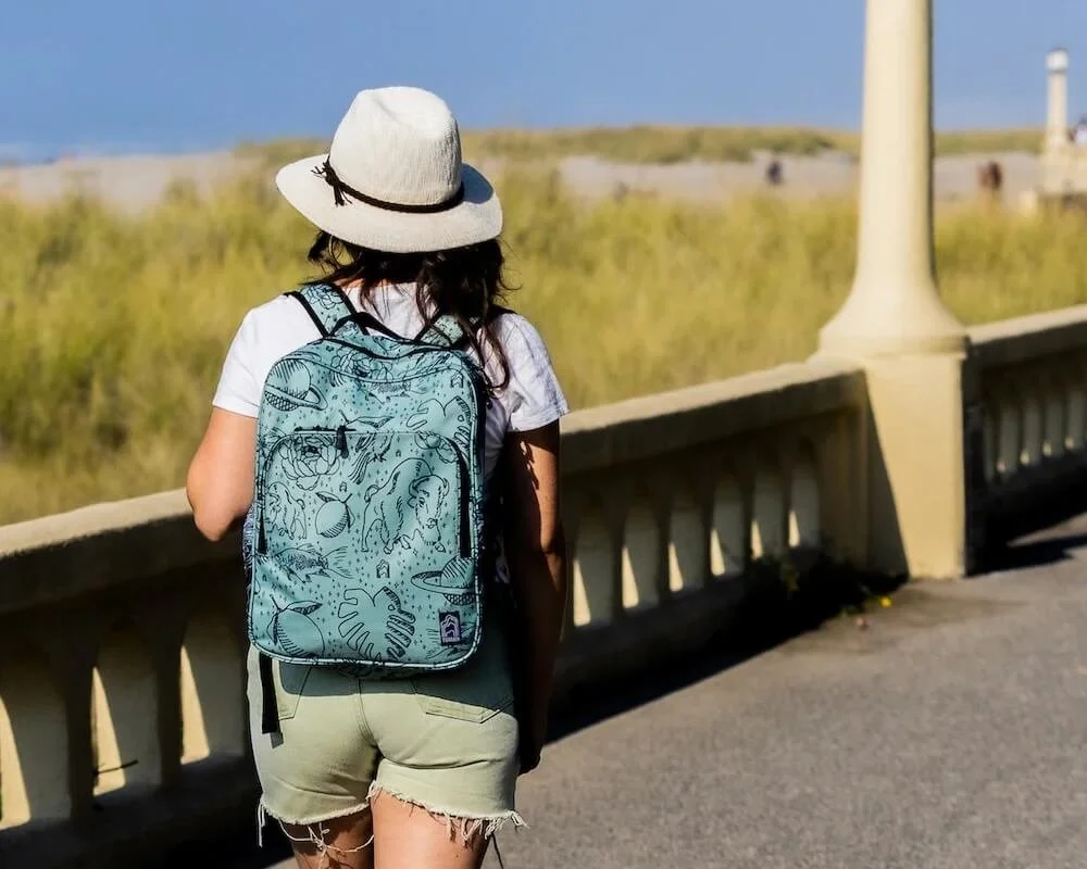 woman wearing teal backpack with custom illustrated pattern