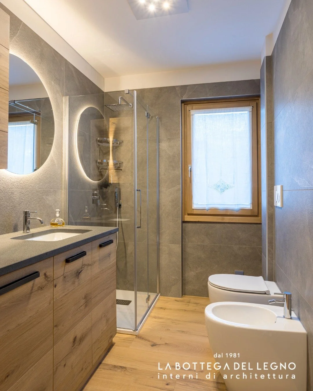 .
𝑫𝒆𝒕𝒕𝒂𝒈𝒍𝒊 𝒄𝒉𝒆 𝒊𝒍𝒍𝒖𝒎𝒊𝒏𝒂𝒏𝒐

Un bagno in continuit&agrave; con l&rsquo;intero progetto.
Mobili in legno su misura dialogano con materiali neutri,
mentre lo specchio tondo retroilluminato aggiunge luce, equilibrio e carattere.

Prog