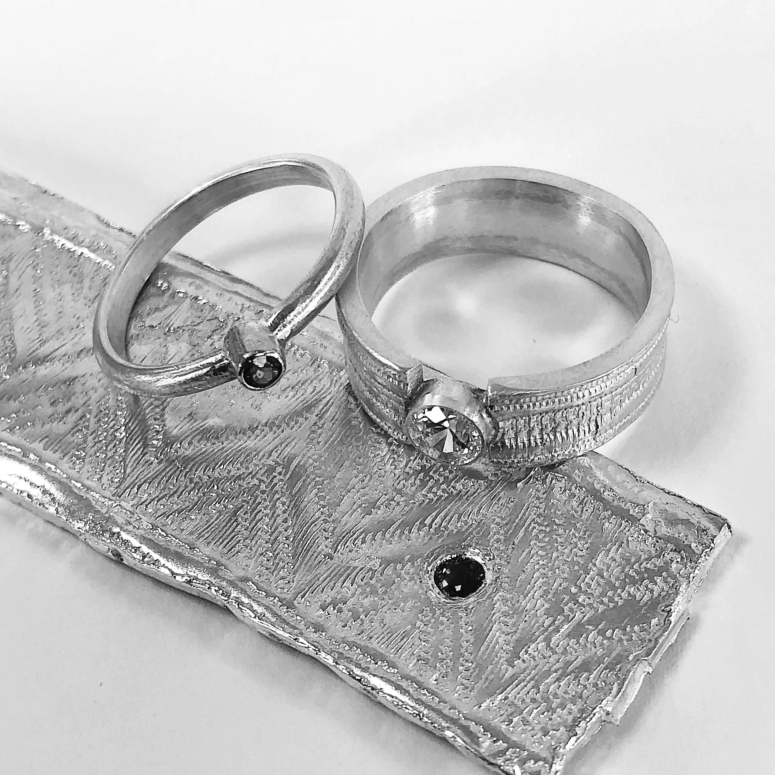 Close-up of silver metallic rings and textured surface on a white background.