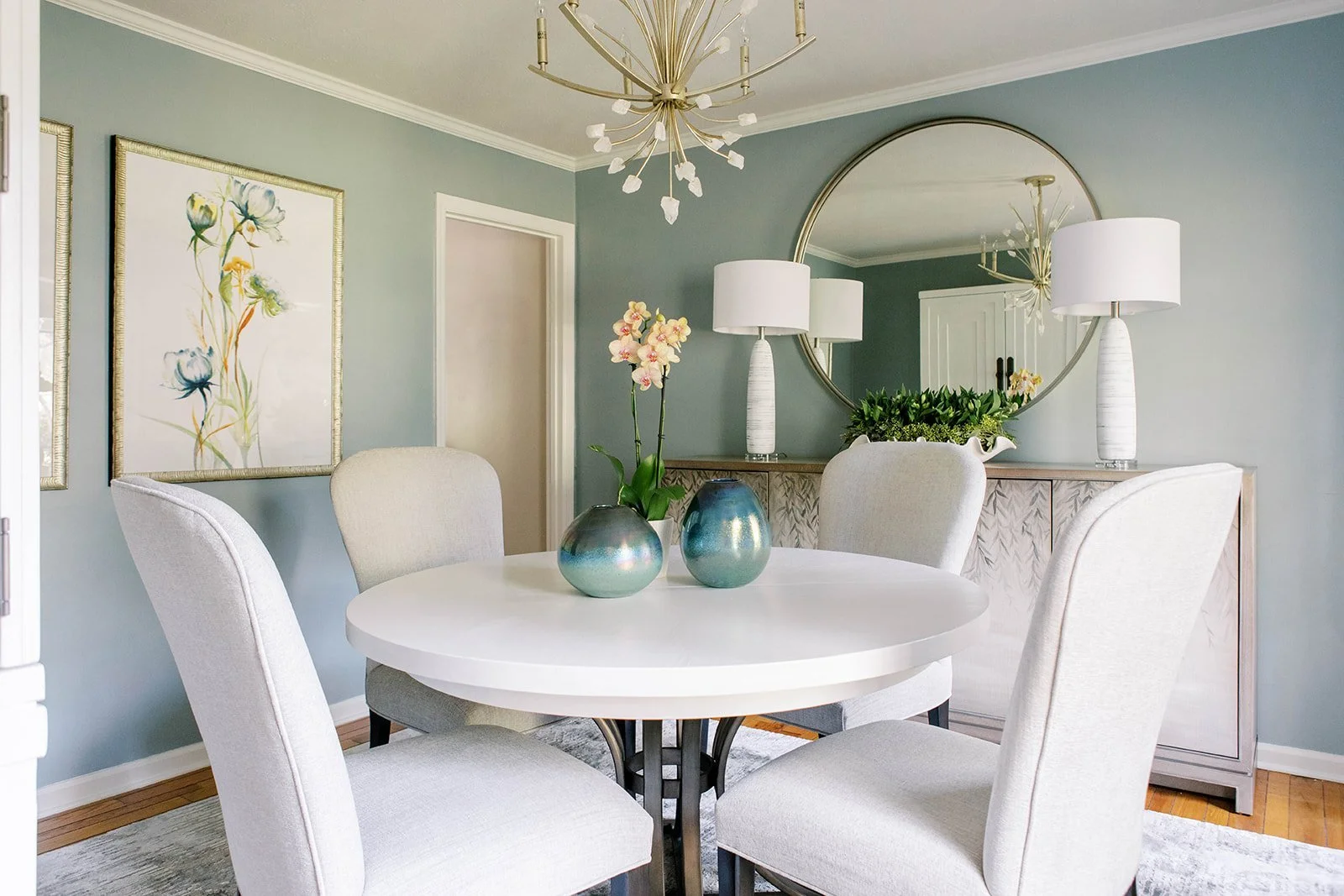 Fully decorated dining space with teal vase at the center of a round table