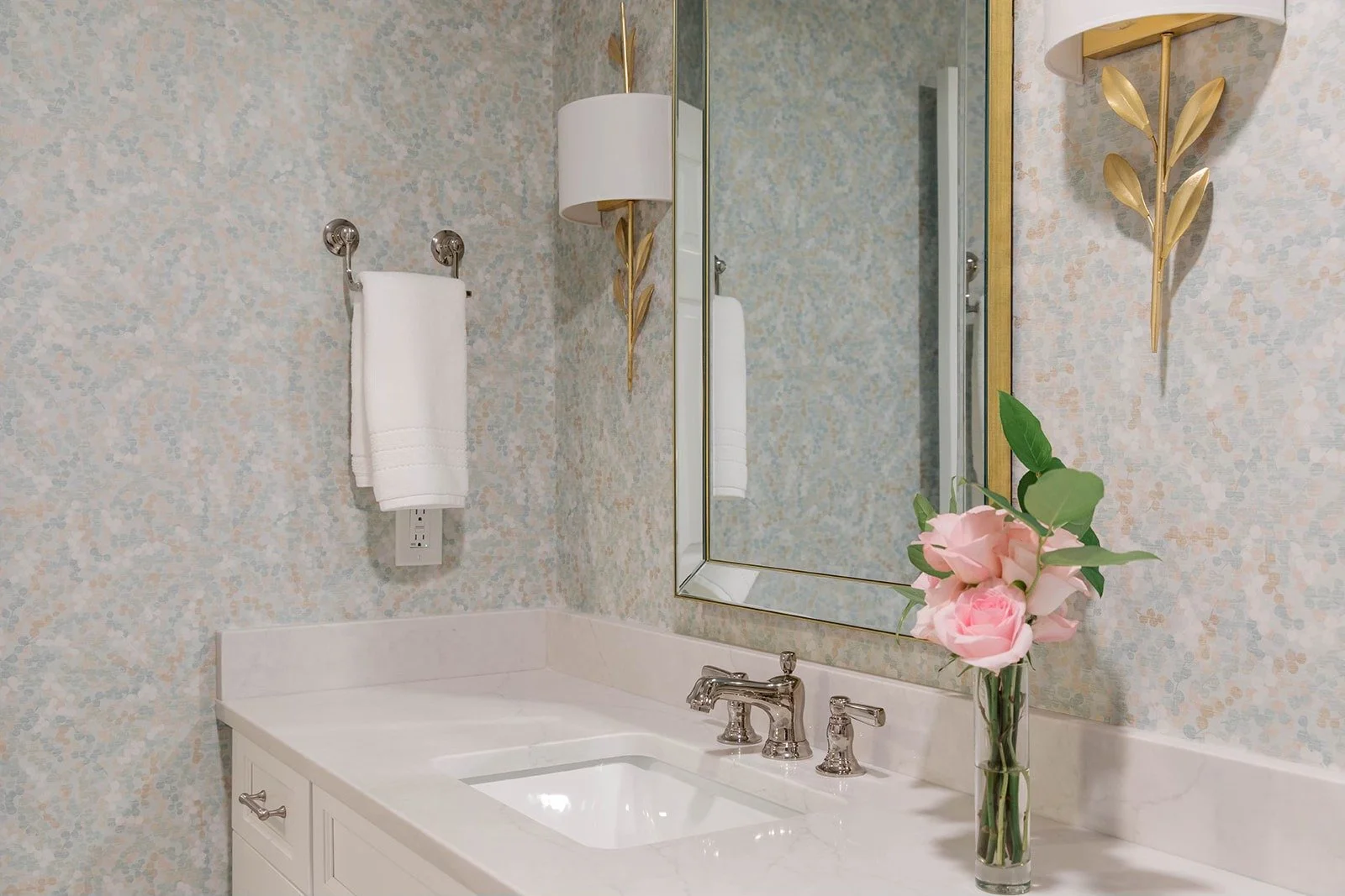 bathroom wallpaper installed with a white counter, mirror and gold sconces