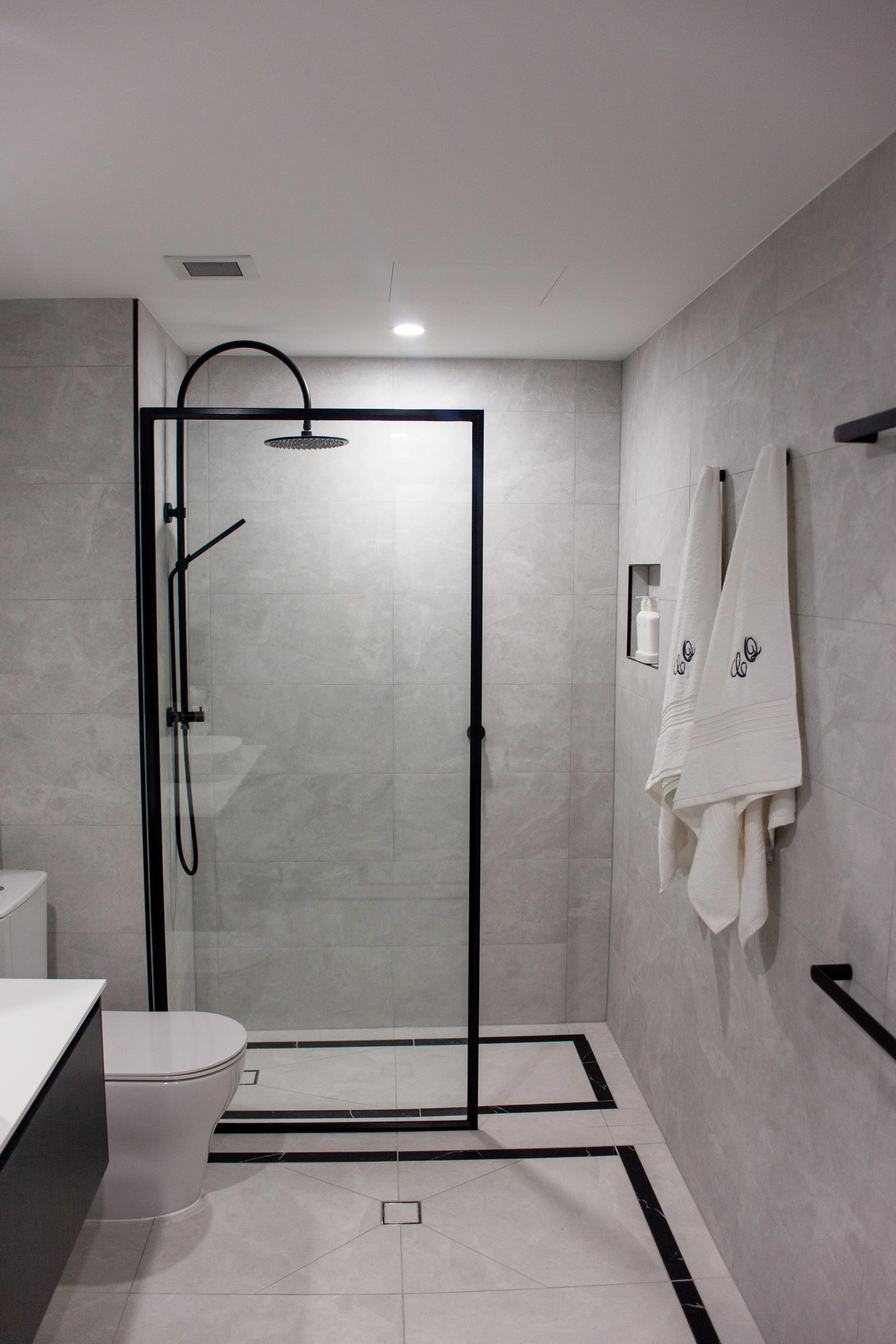 Floor to ceiling stone look tile details bathroom renovation by Riise Group