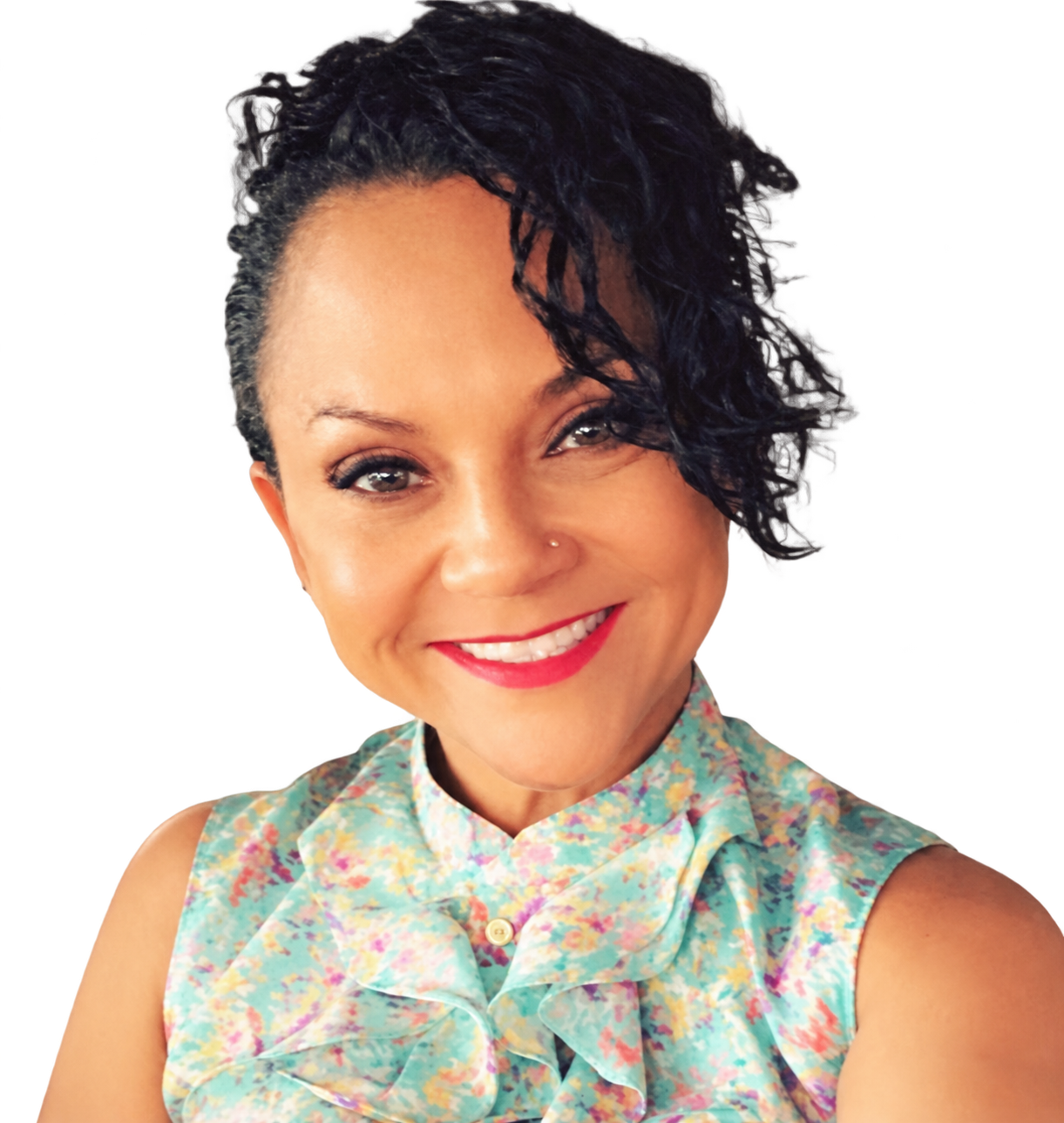 Smiling person in floral blouse, indoor setting with brick wall and decorative shelves in background