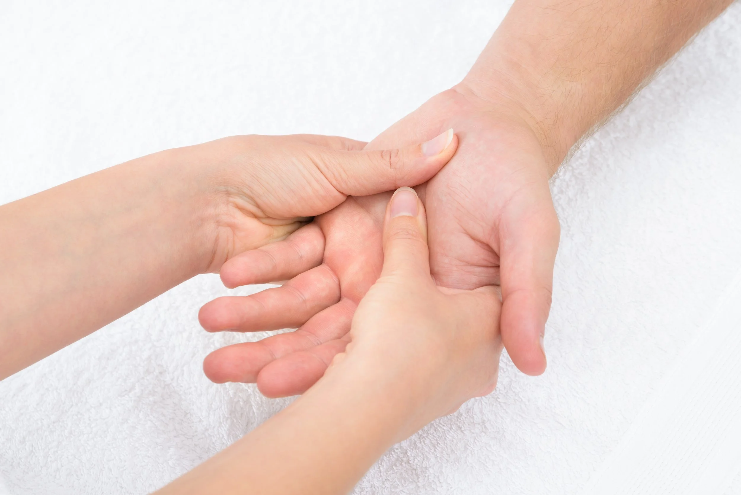 Close-up of a hand receiving a massage, focusing on the palm and fingers on a white background.