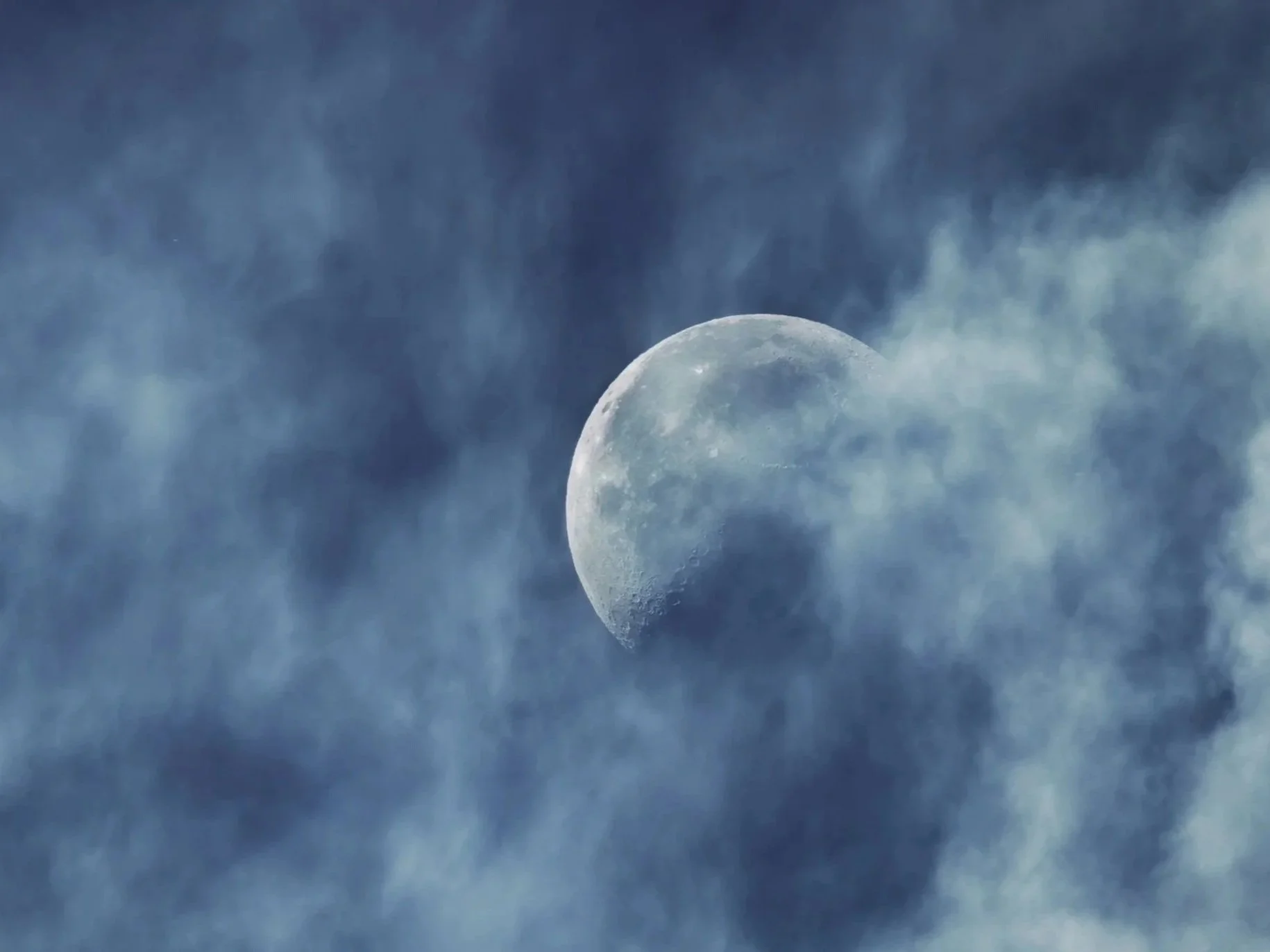 Moon partially obscured by clouds in a night sky.