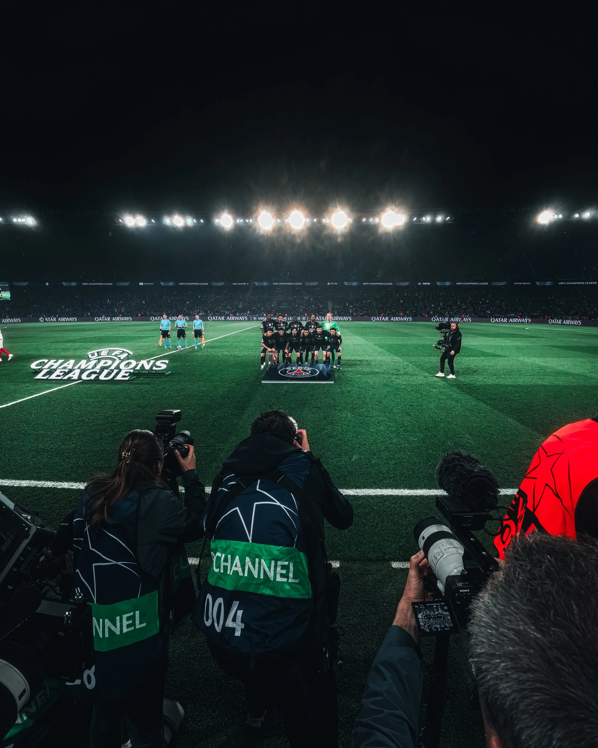 Photo d'une équipe de football posant pour une photo officielle sur le terrain lors d'un match de la Ligue des champions de l'UEFA, avec des journalistes photographes en premier plan.