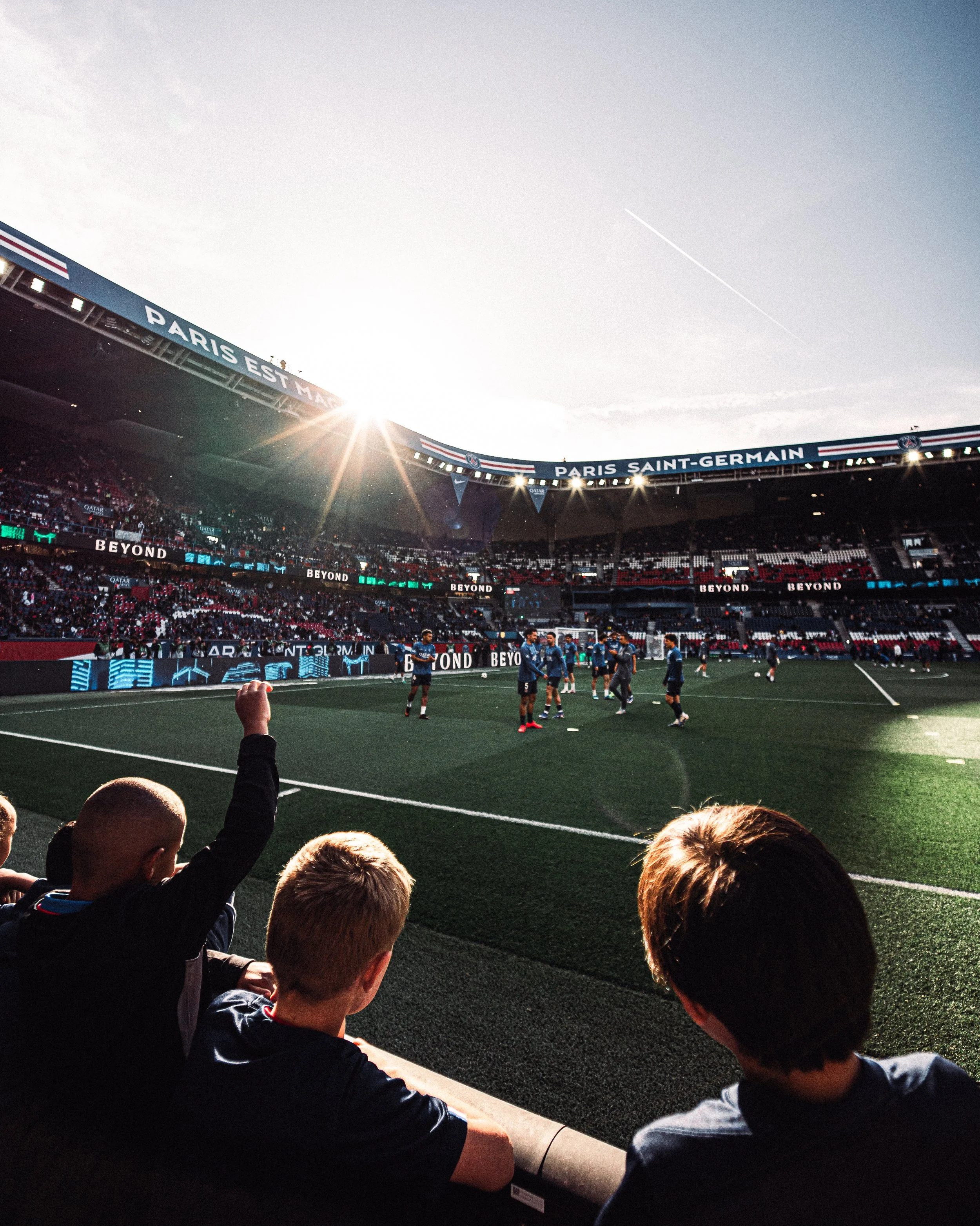 Photo d’un match de football au stade Paris Saint-Germain avec des joueurs sur le terrain et des spectateurs dans les gradins.