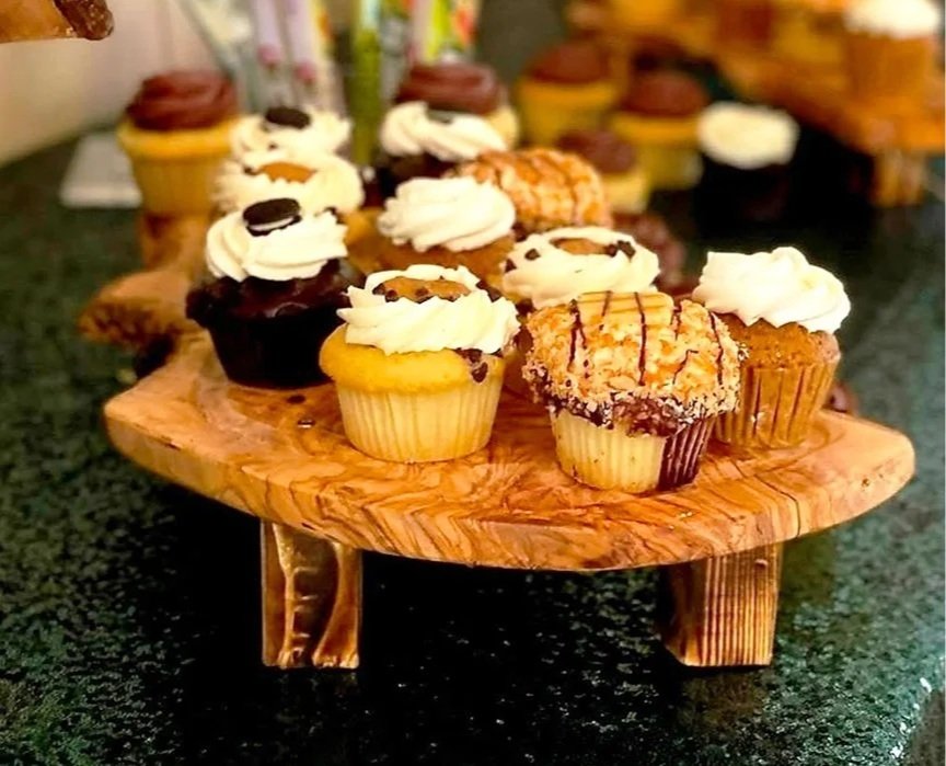Assorted cupcakes with frosting and toppings on a wooden display stand.