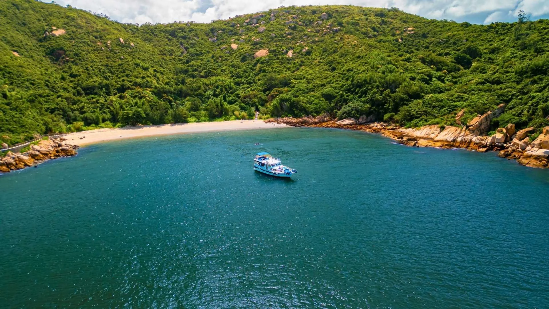 A junk boat near the golden sands of Tung Wan Beach in Cheung Chau, showing the vibrant island coastline.