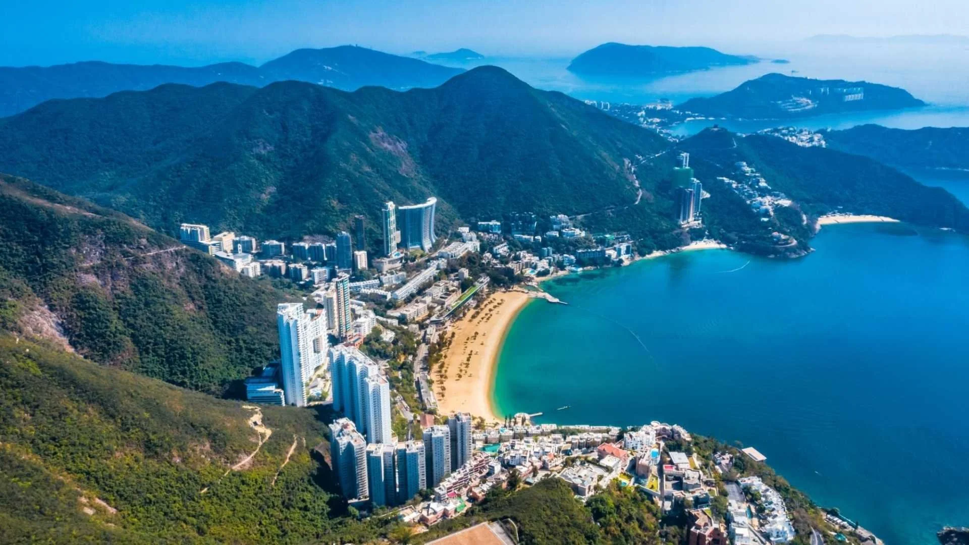 A luxury junk boat drifting in Repulse Bay with the iconic designer skyline and sandy beach in the background.