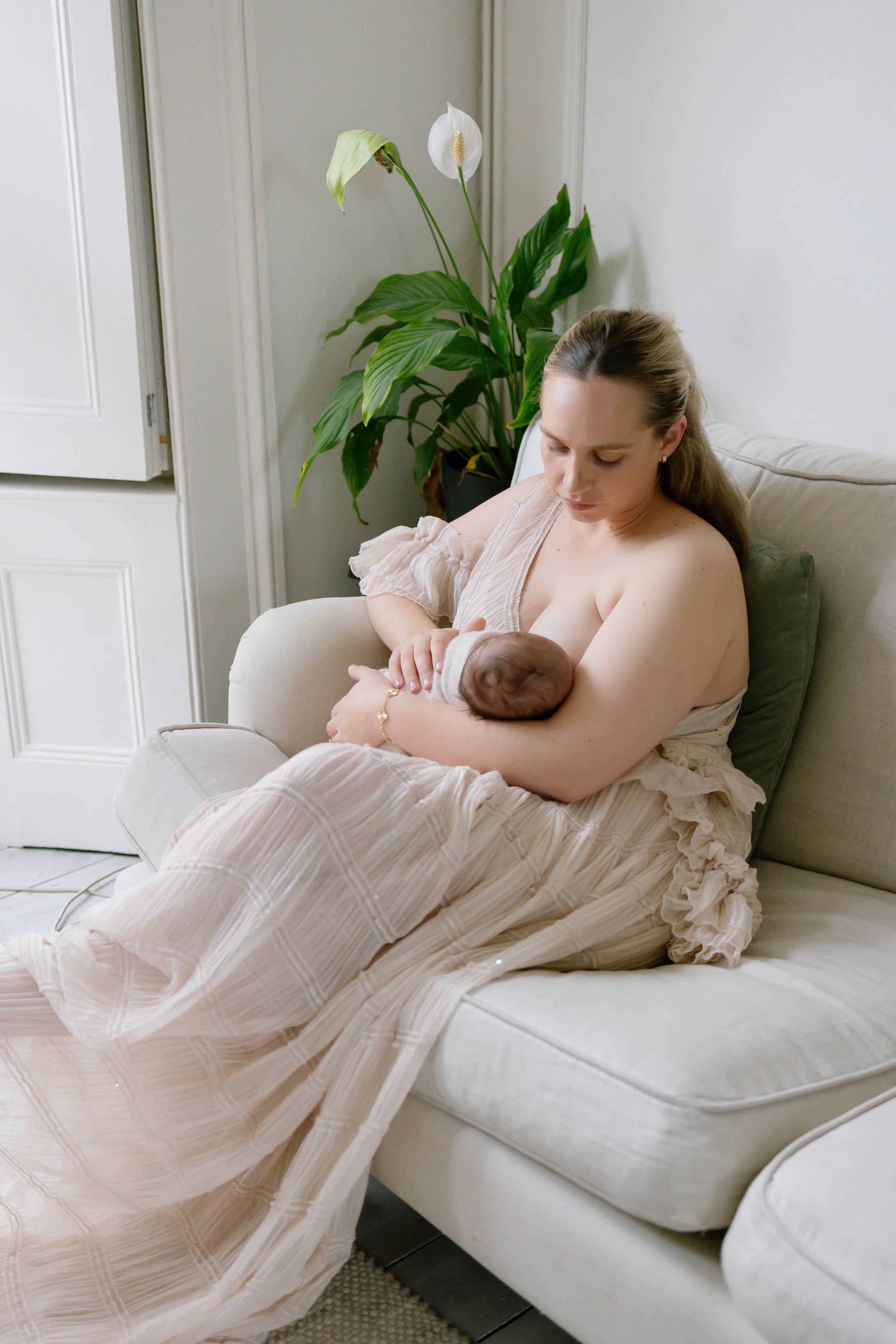 New mum breastfeeds baby on sofa