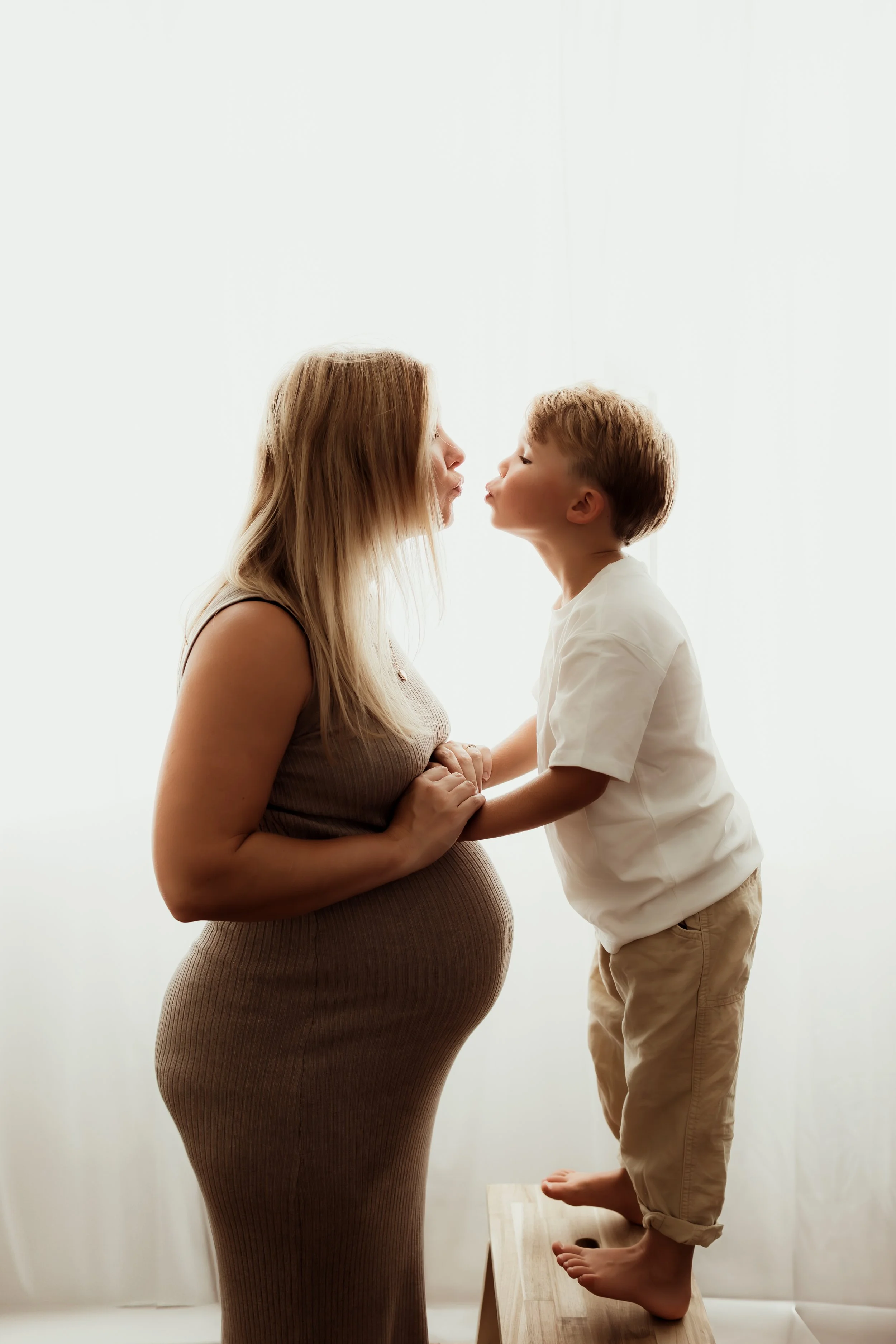 A pregnant woman with her son, holding hands during maternity photoshoot in Salisbury studio