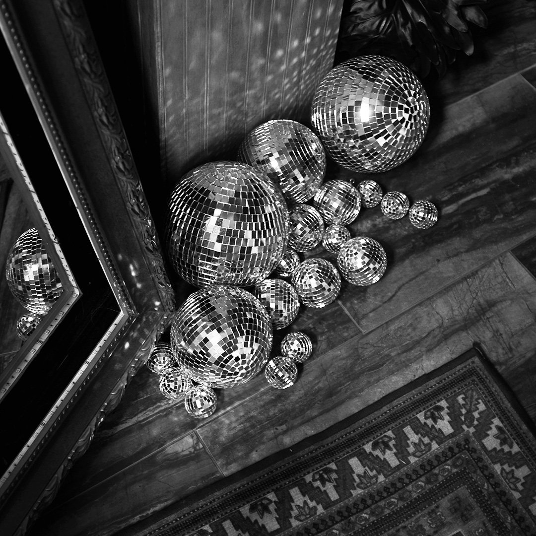 Disco balls in front of the mirror mirror photo booth letting the wedding guests know how much fun they're about to have.