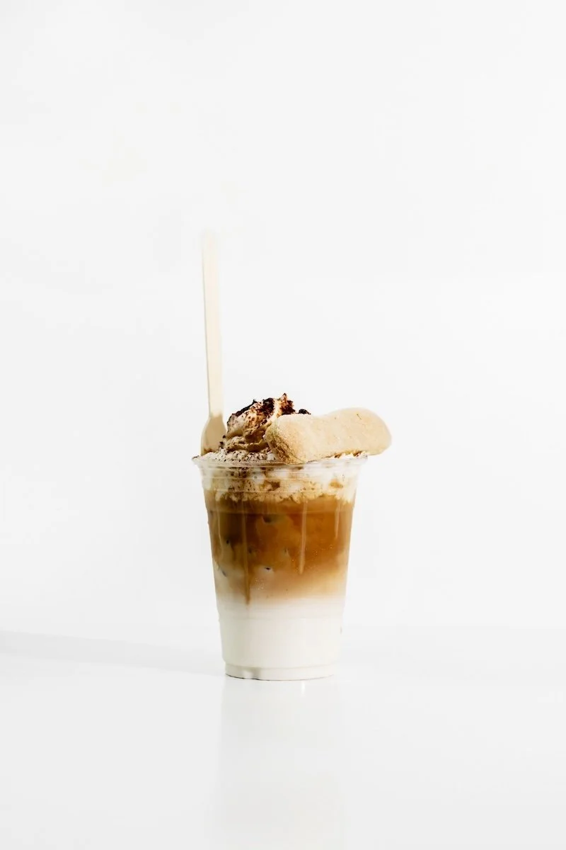 Tiramisu latte topped with cream and a lady finger