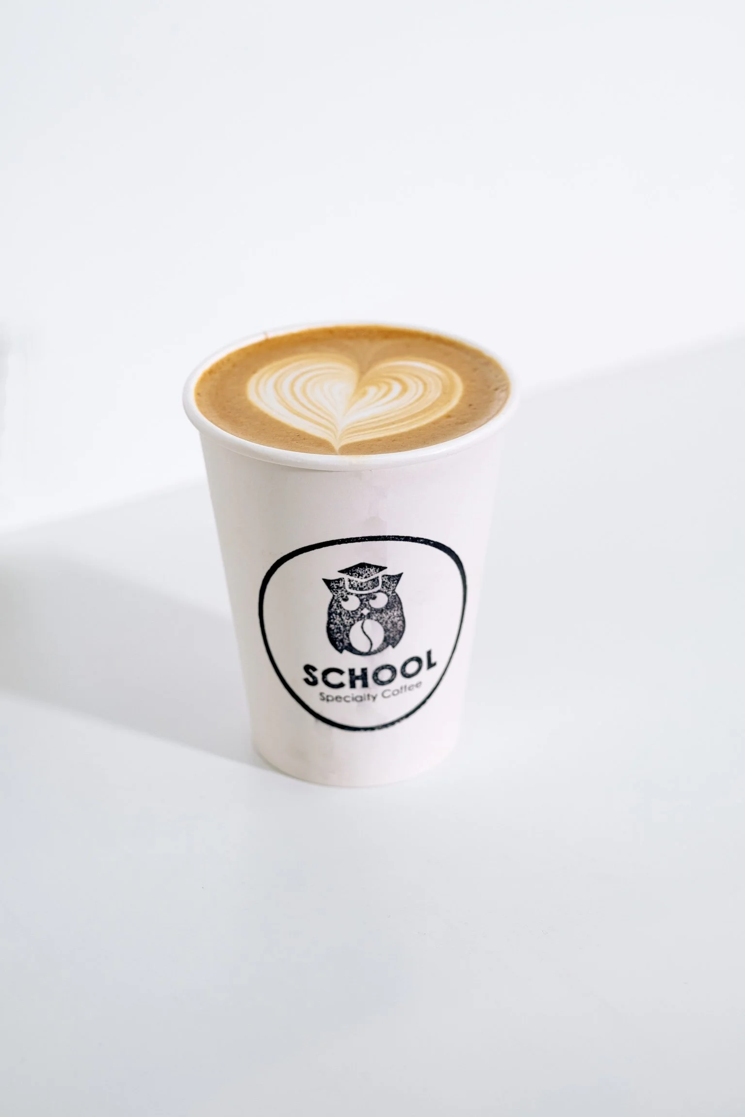 Latte with heart-shaped foam art in a School Specialty Coffee cup