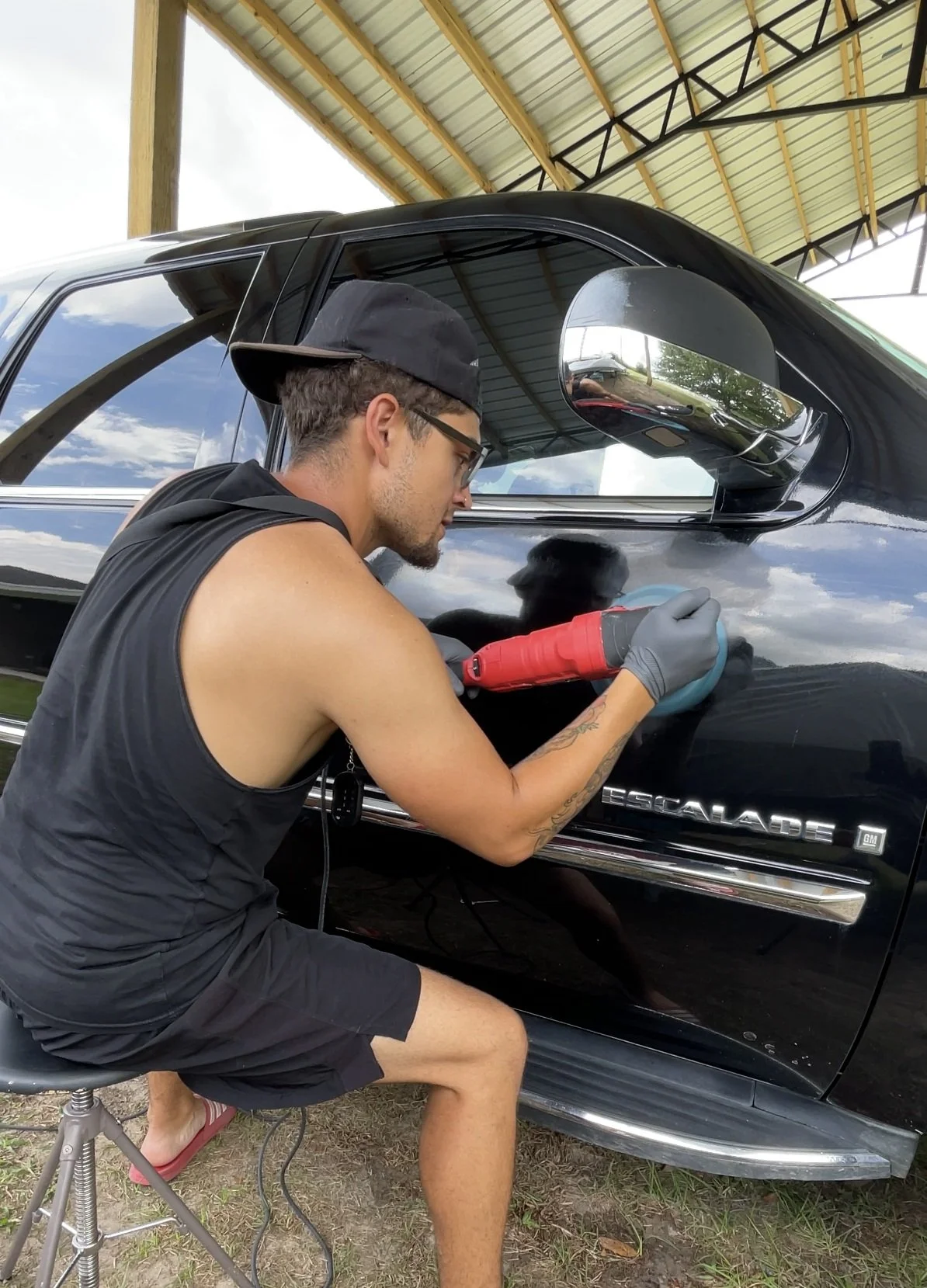 Paint correction being performed on a black Cadillac Escalade using a dual-action polisher to remove swirl marks and restore gloss.