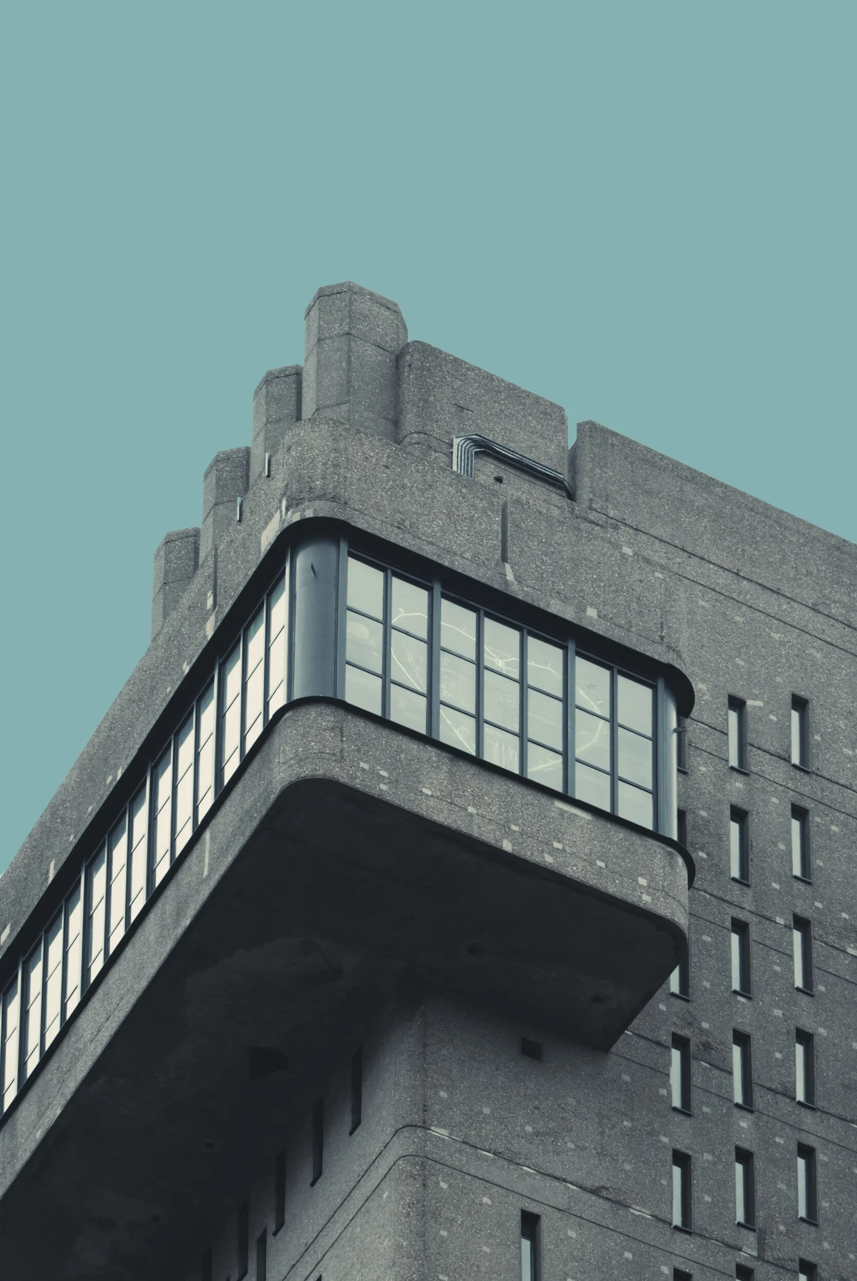 Image from unsplash.com of the corner of a windowed building with a soft blue sky