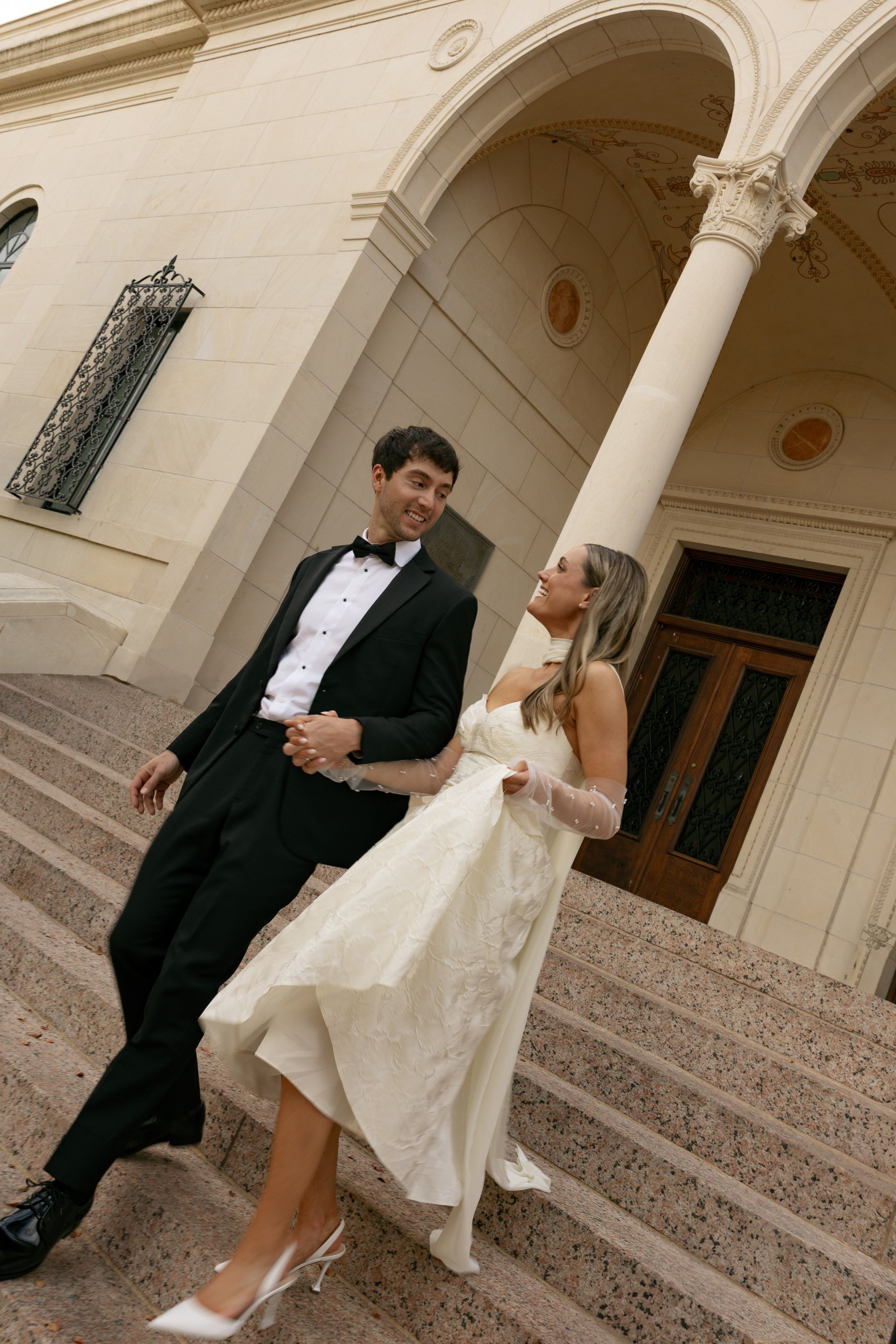 austin wedding couple, bride and groom holding hands running out of the Austin Library