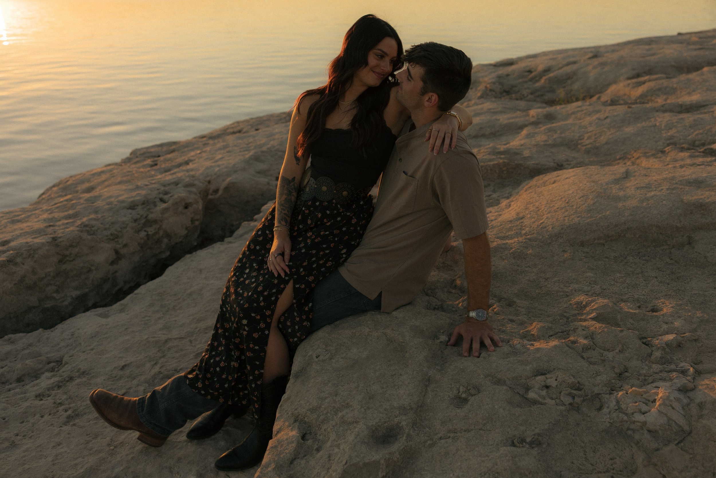 engaged couple, girl in long skirt sitting on boy's lap by the Georgetown Overlook water line