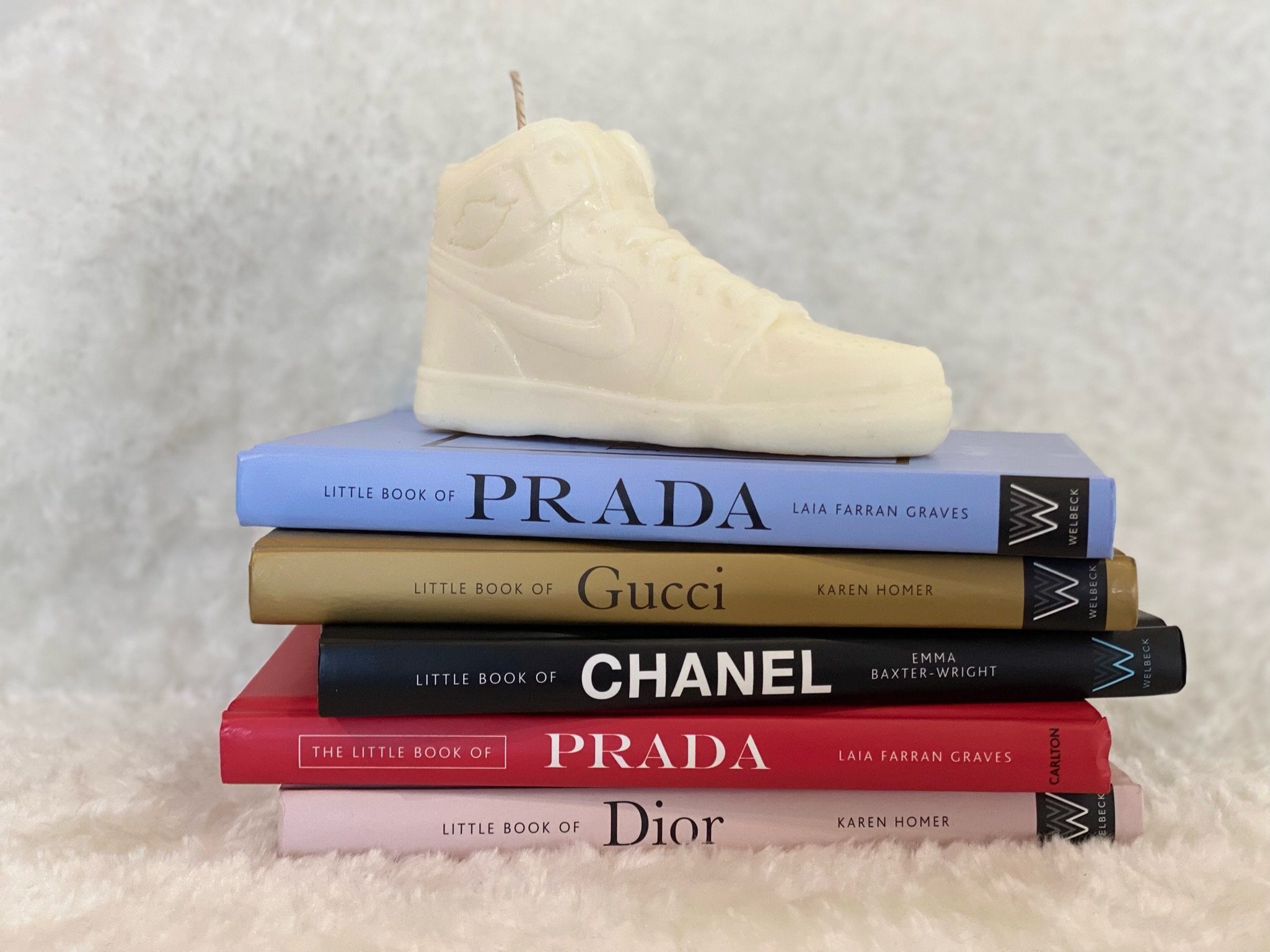 Stack of five fashion books with a white sneaker on top.