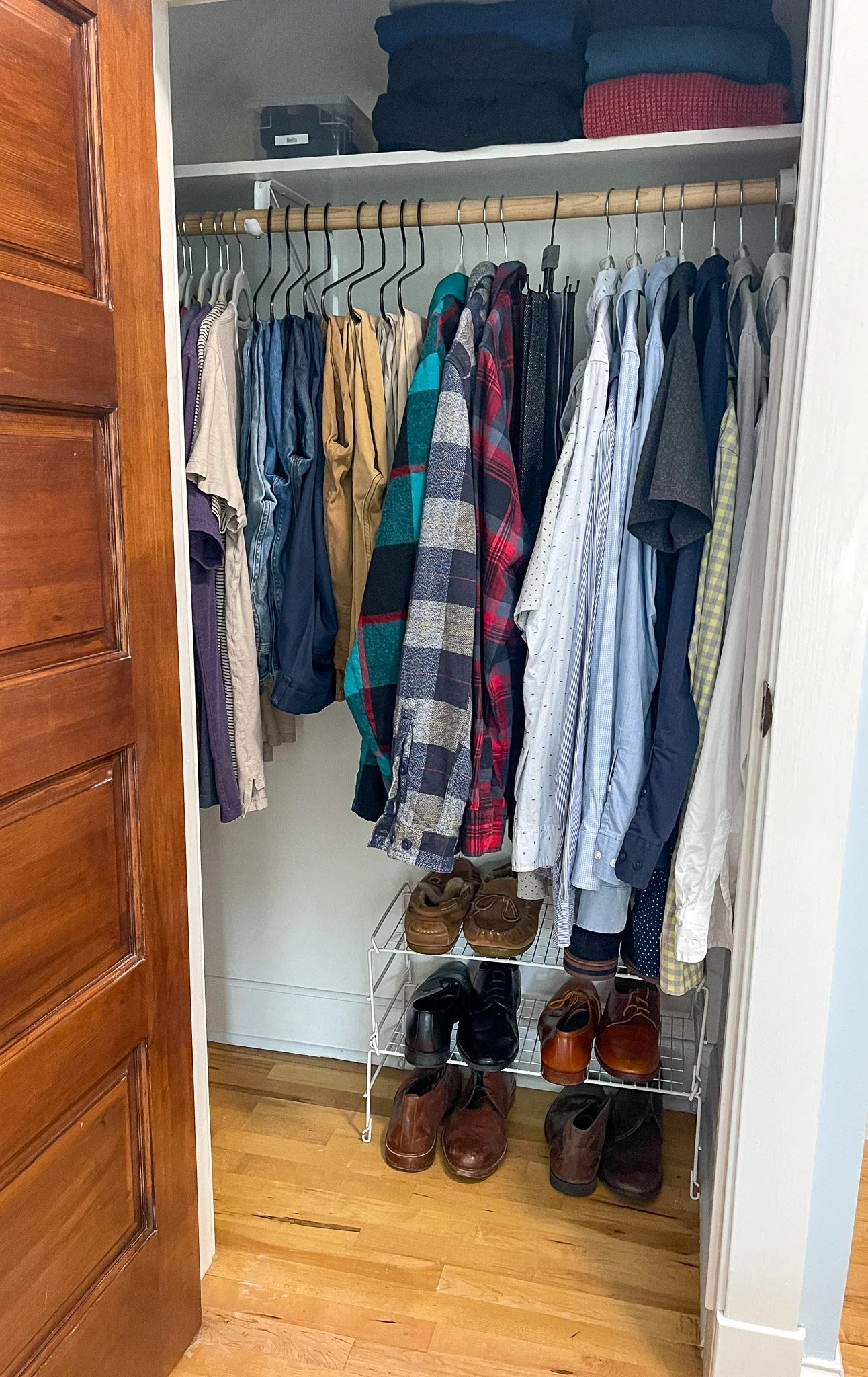 Small men’s closet organized with streamlined hanging storage