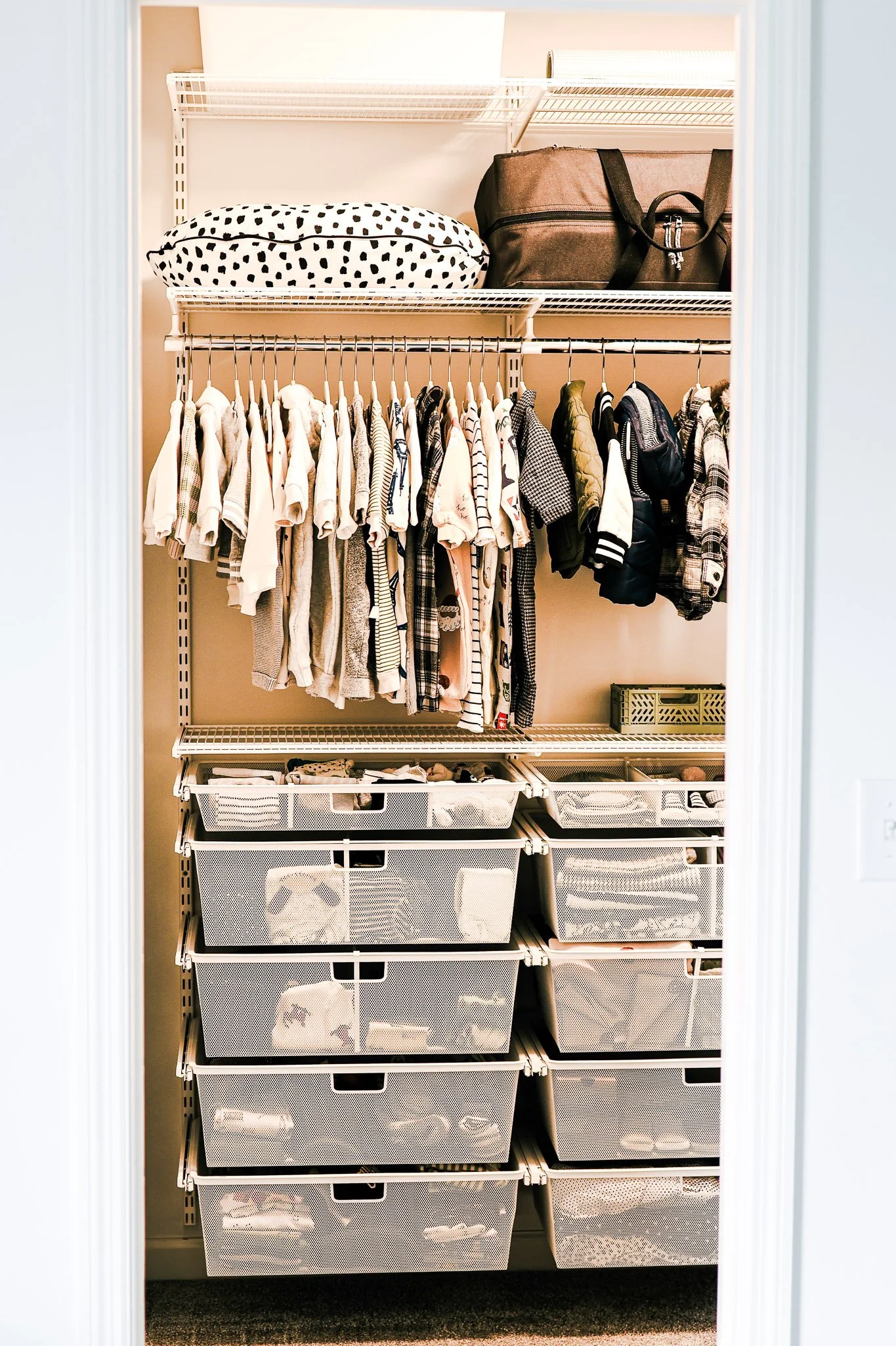 Nursery closet organized with custom storage for baby items