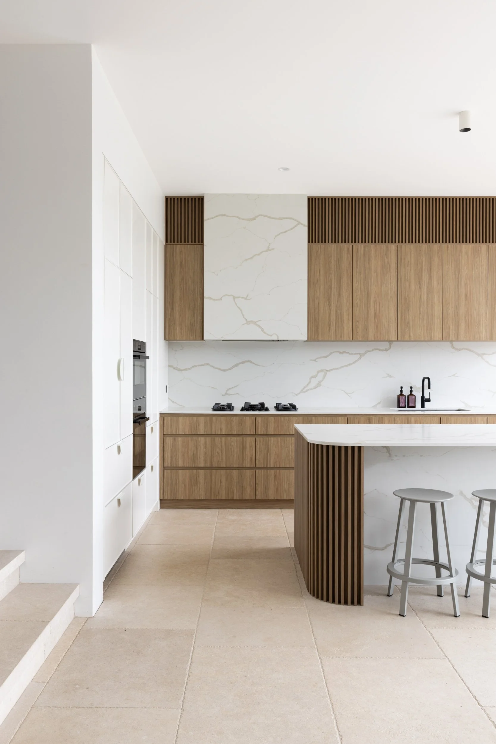 Contemporary kitchen renovation with natural timber cabinetry, white stone benchtops and a sculptural island.
