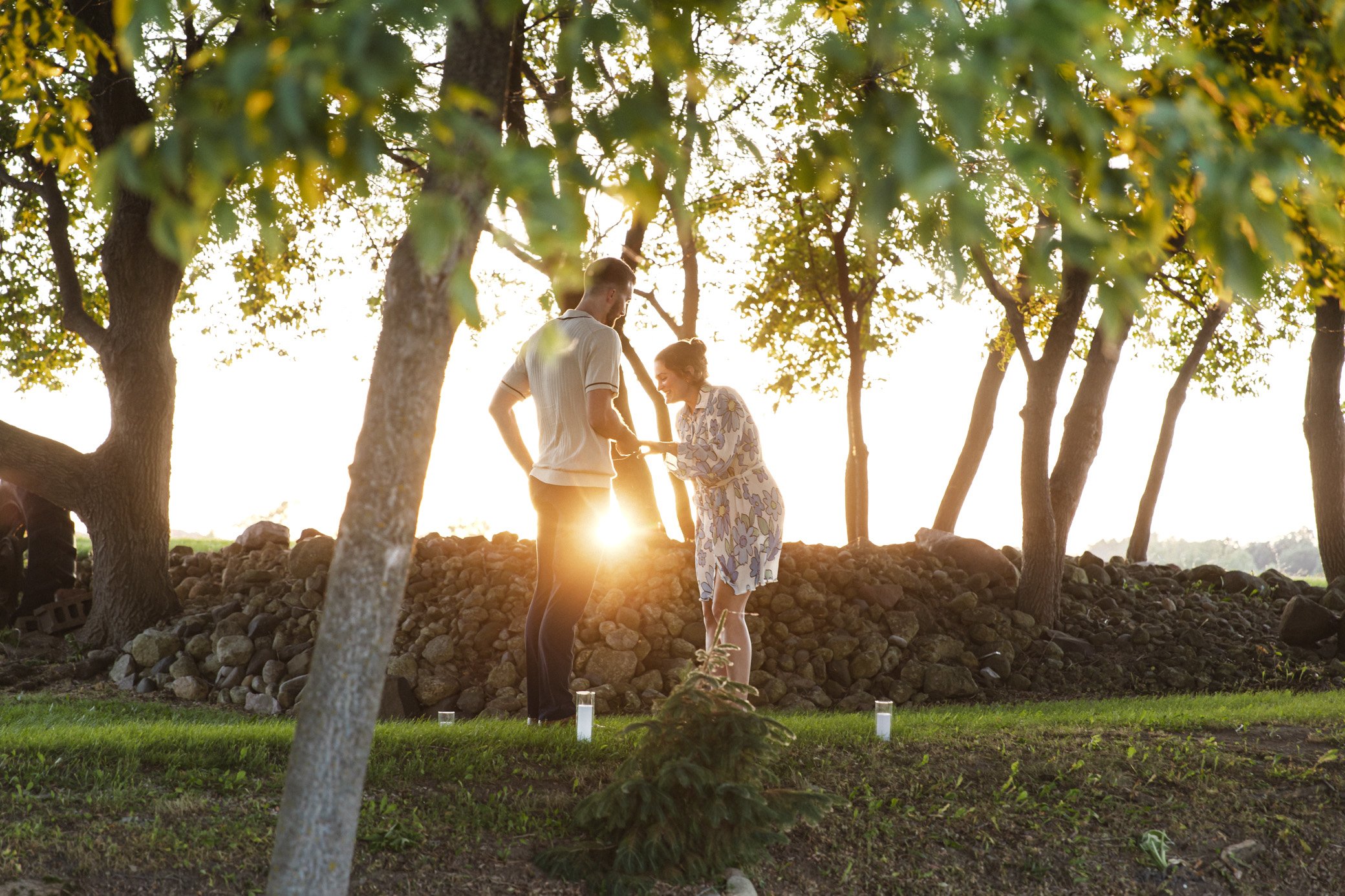 A couple being married in a small outdoor ceremony at sunset, with trees and candles around them.
