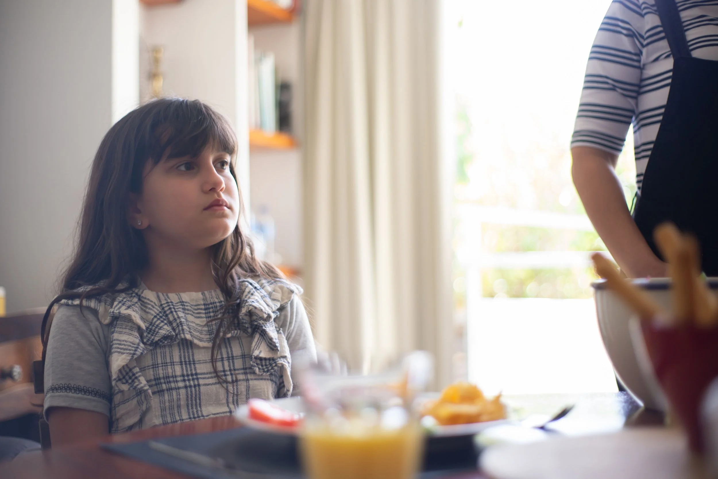 girl with school anxiety sits at the breakfast table staring into the distance
