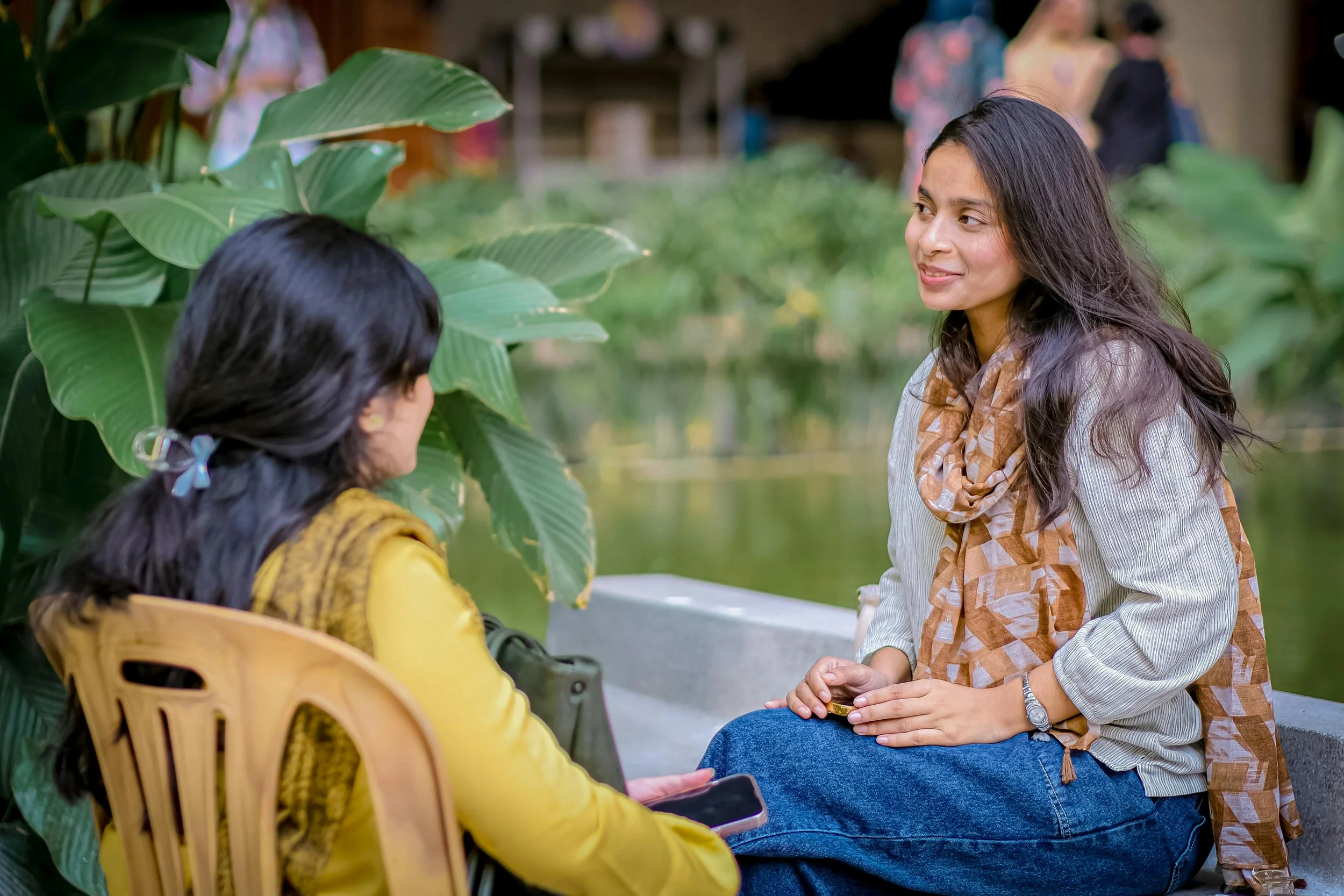 two women are sitting outside across from each other