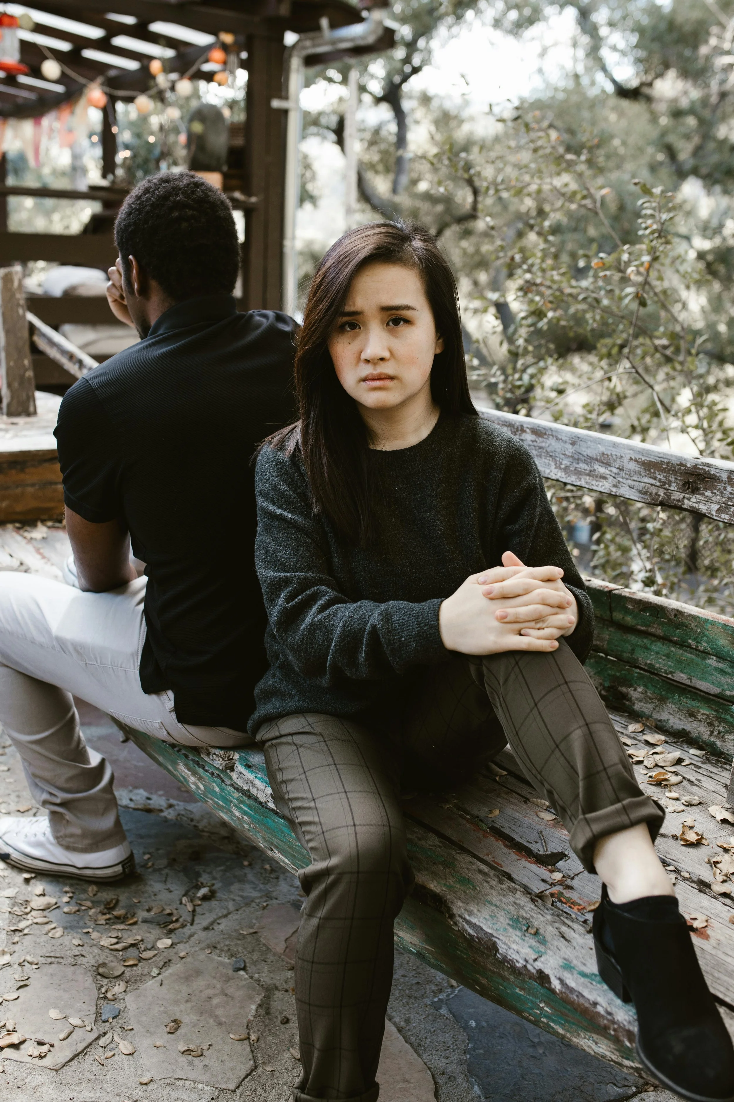 a woman is seated with her back against a man and her face is upset