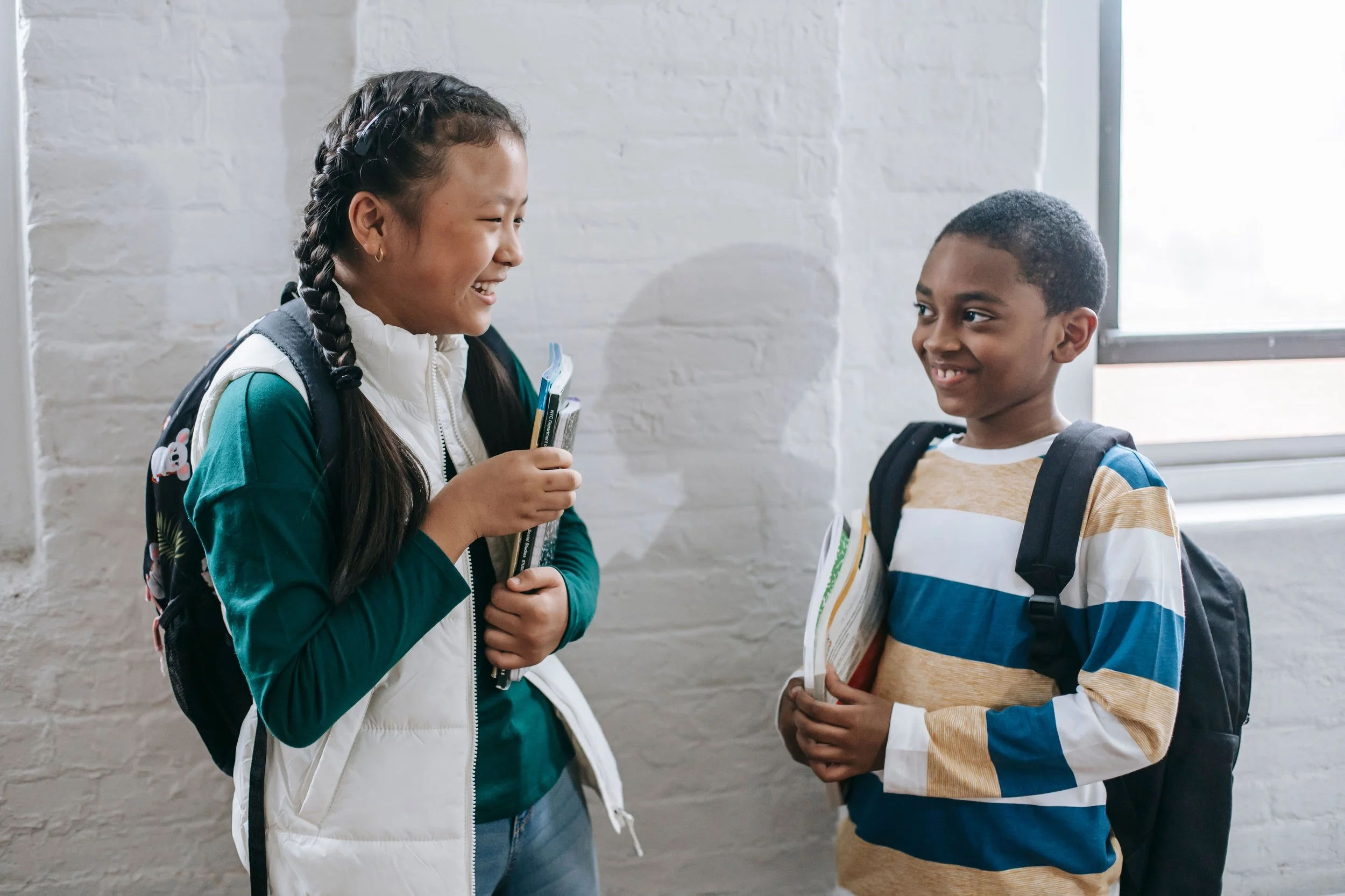 two children with back to school anxiety are in the school hallway smiling at each other