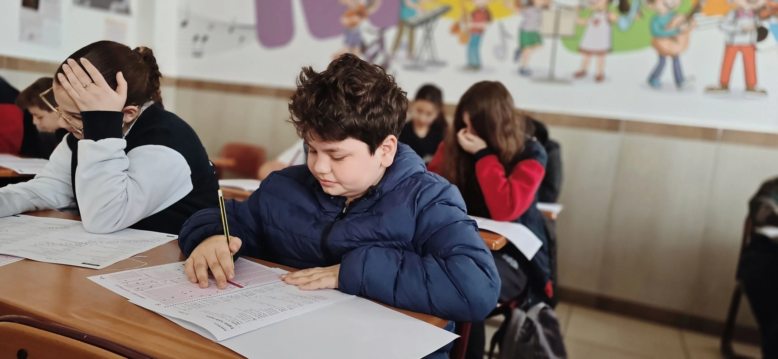 children in a classroom taking a test, the boy in the front has back to school anxiety